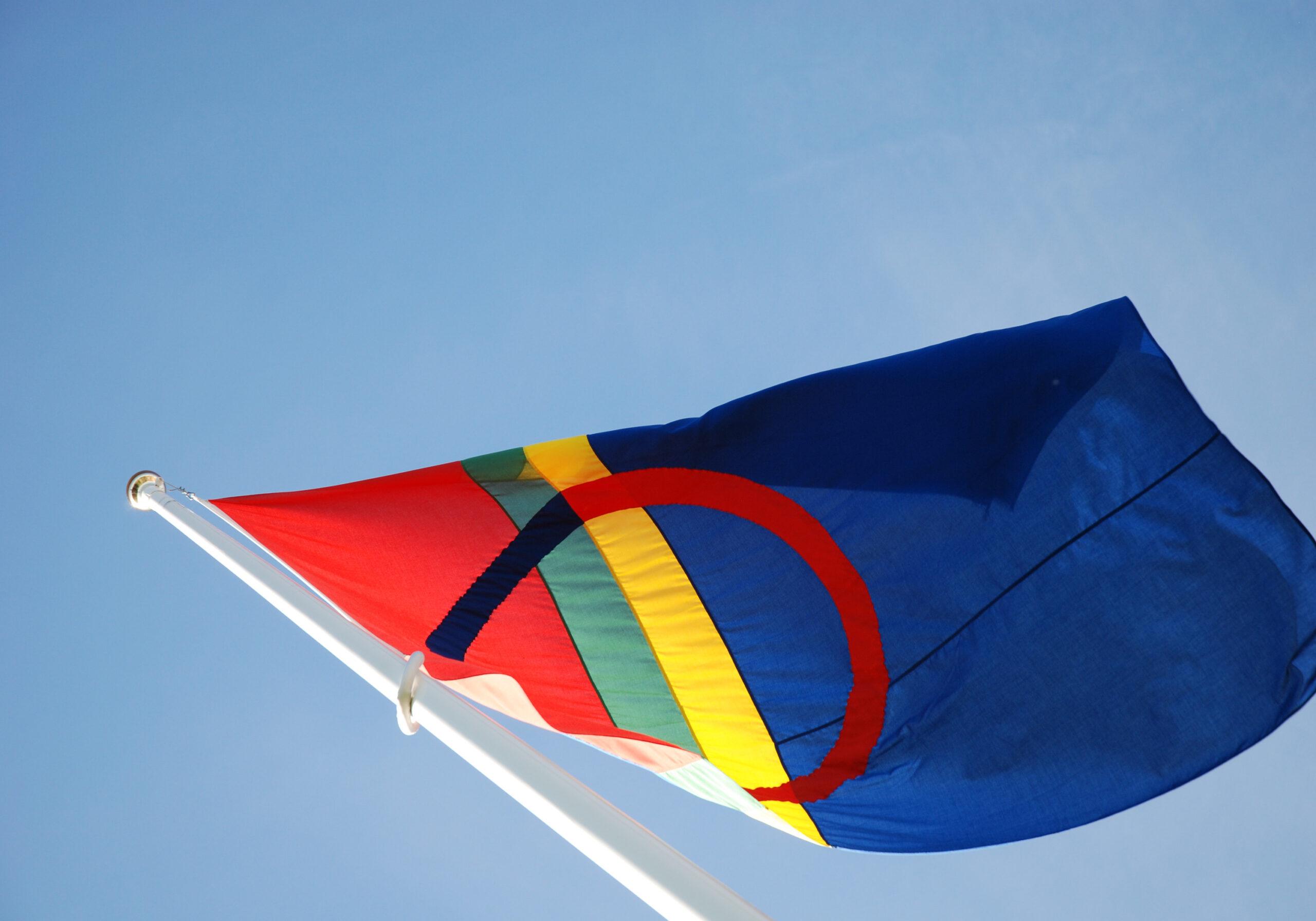 The Sami flag - red, blue, green and yellow – blowing in the wind.