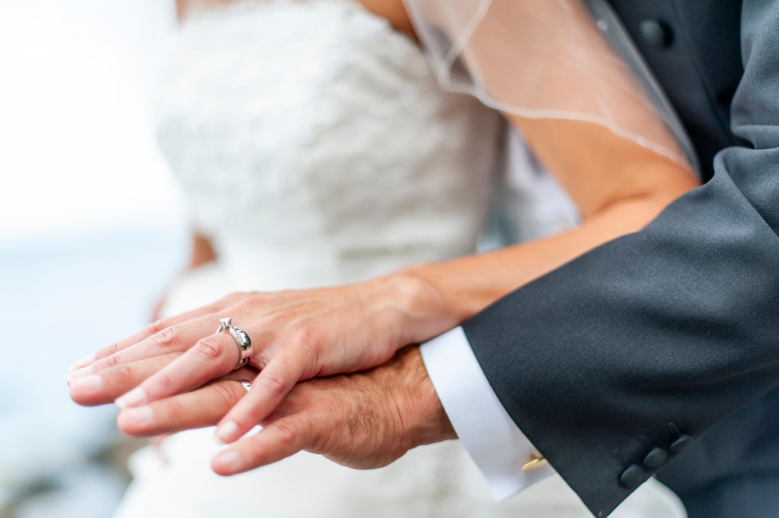 Close-up of a man and woman with wedding bands.