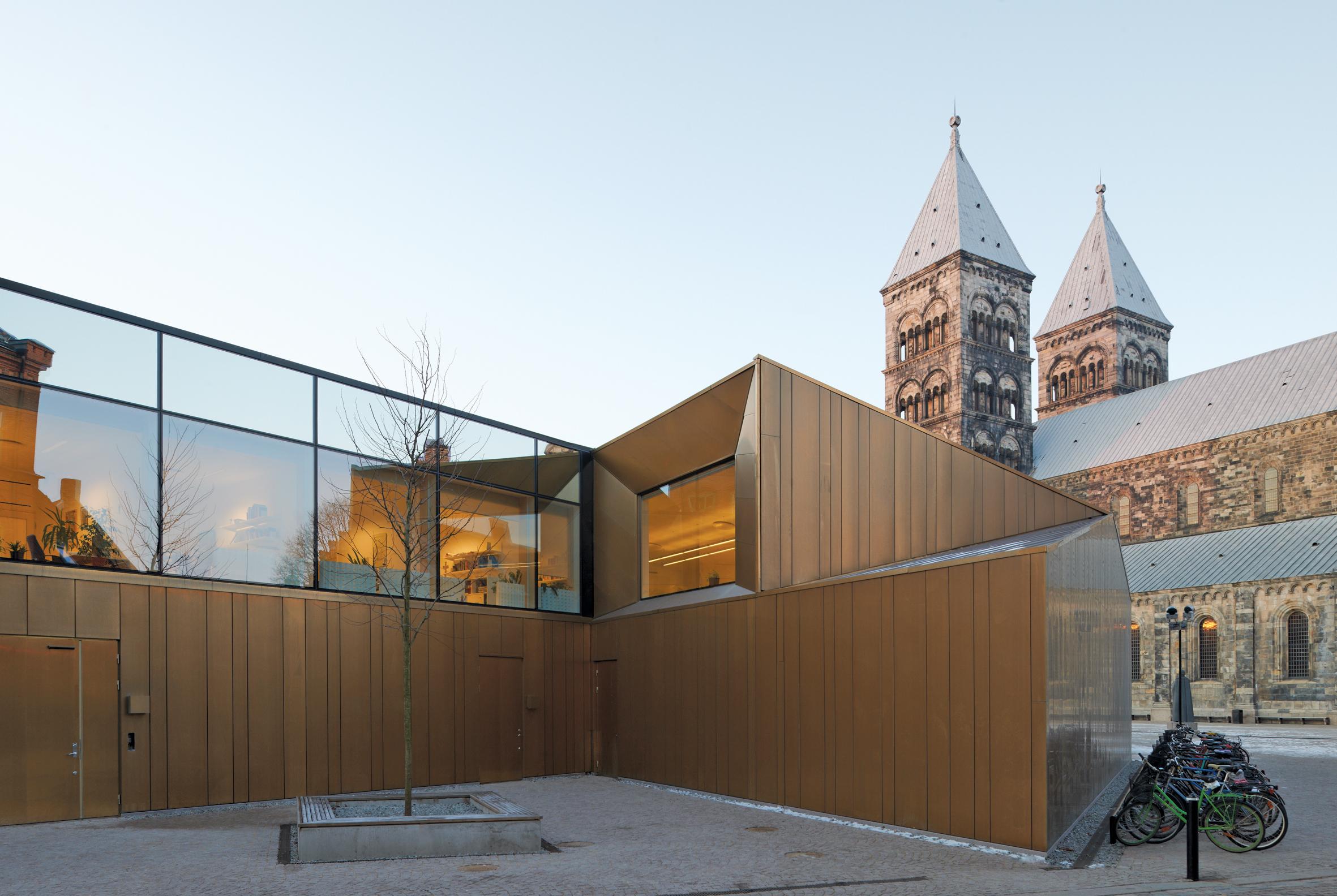 A modern, square building in front of a traditional cathedral building.