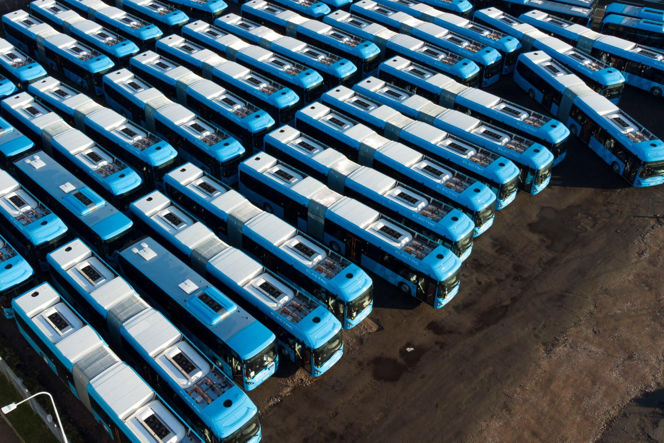 Aerial view of lots of buses parked close together.