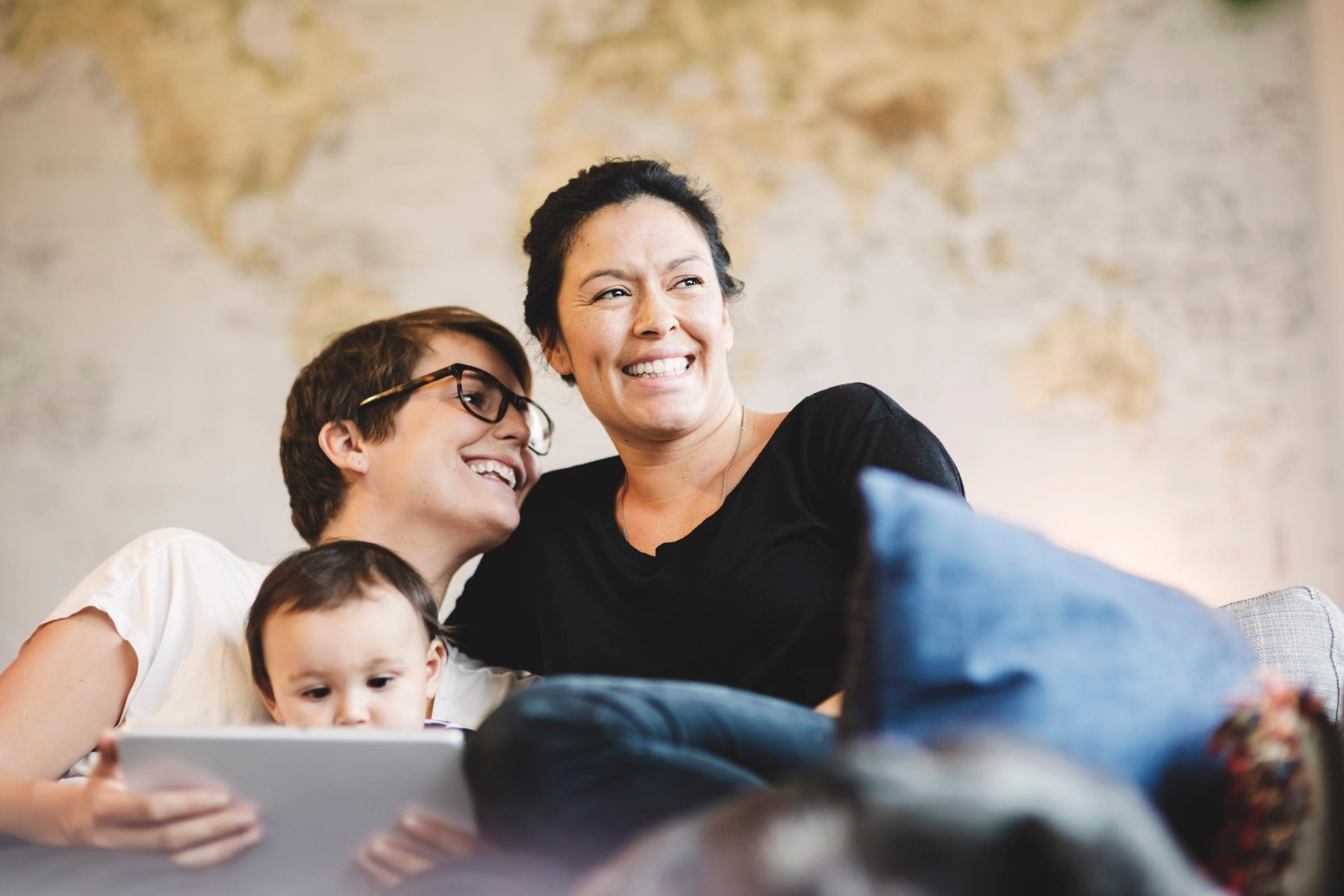 Two women smiling next to a child.