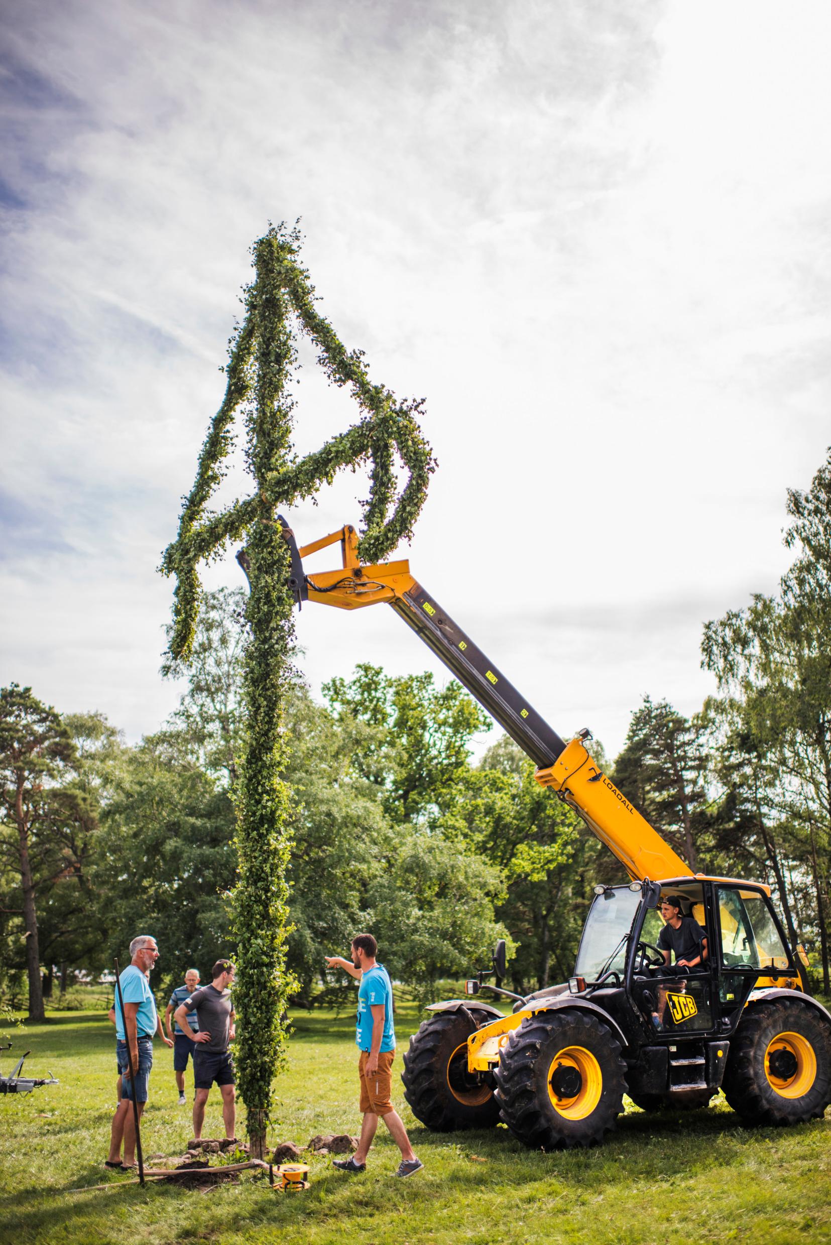 A Midsummer pole being erected using a small crane.