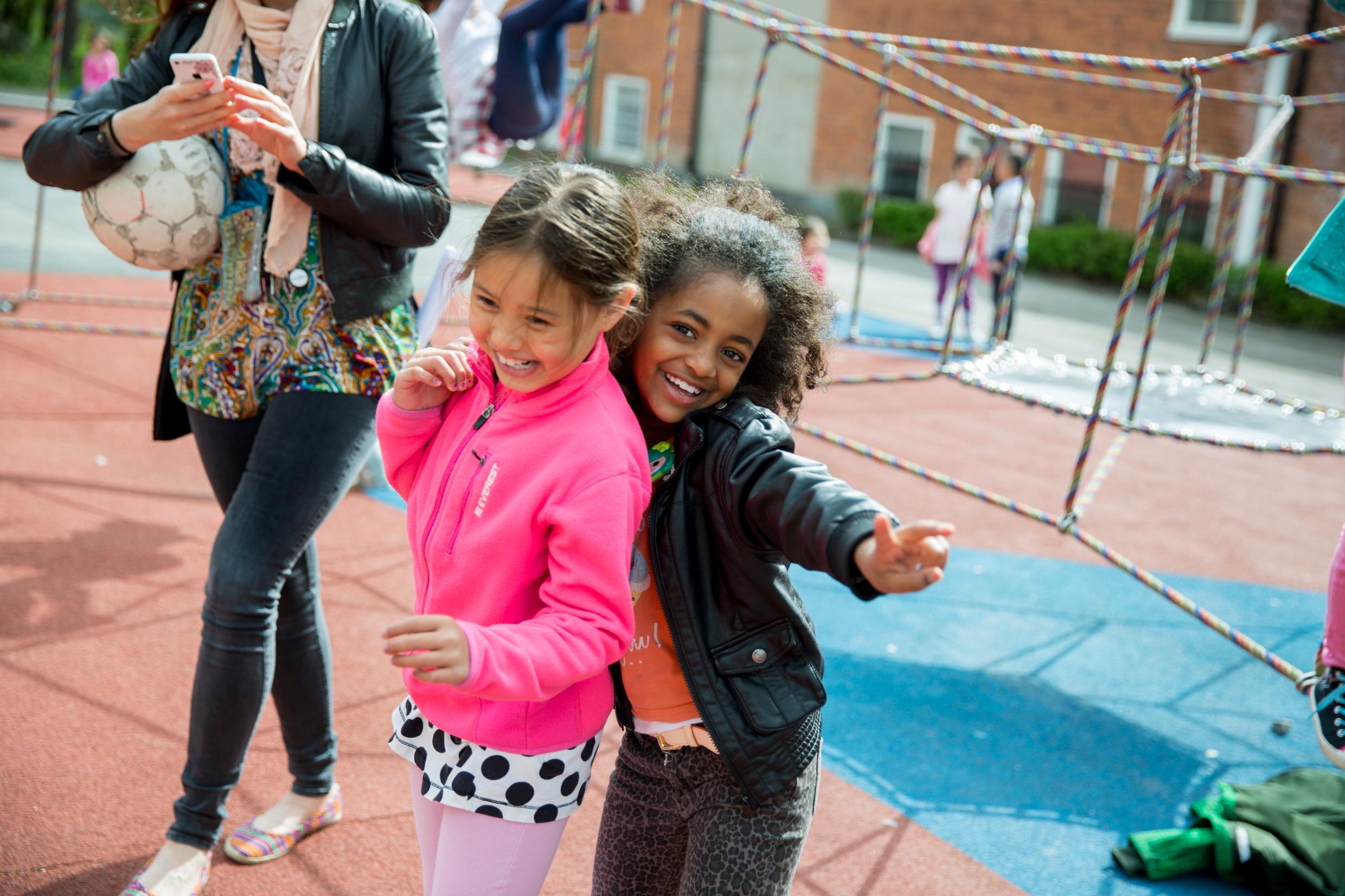 Two young girls playing together in a schoolyard.