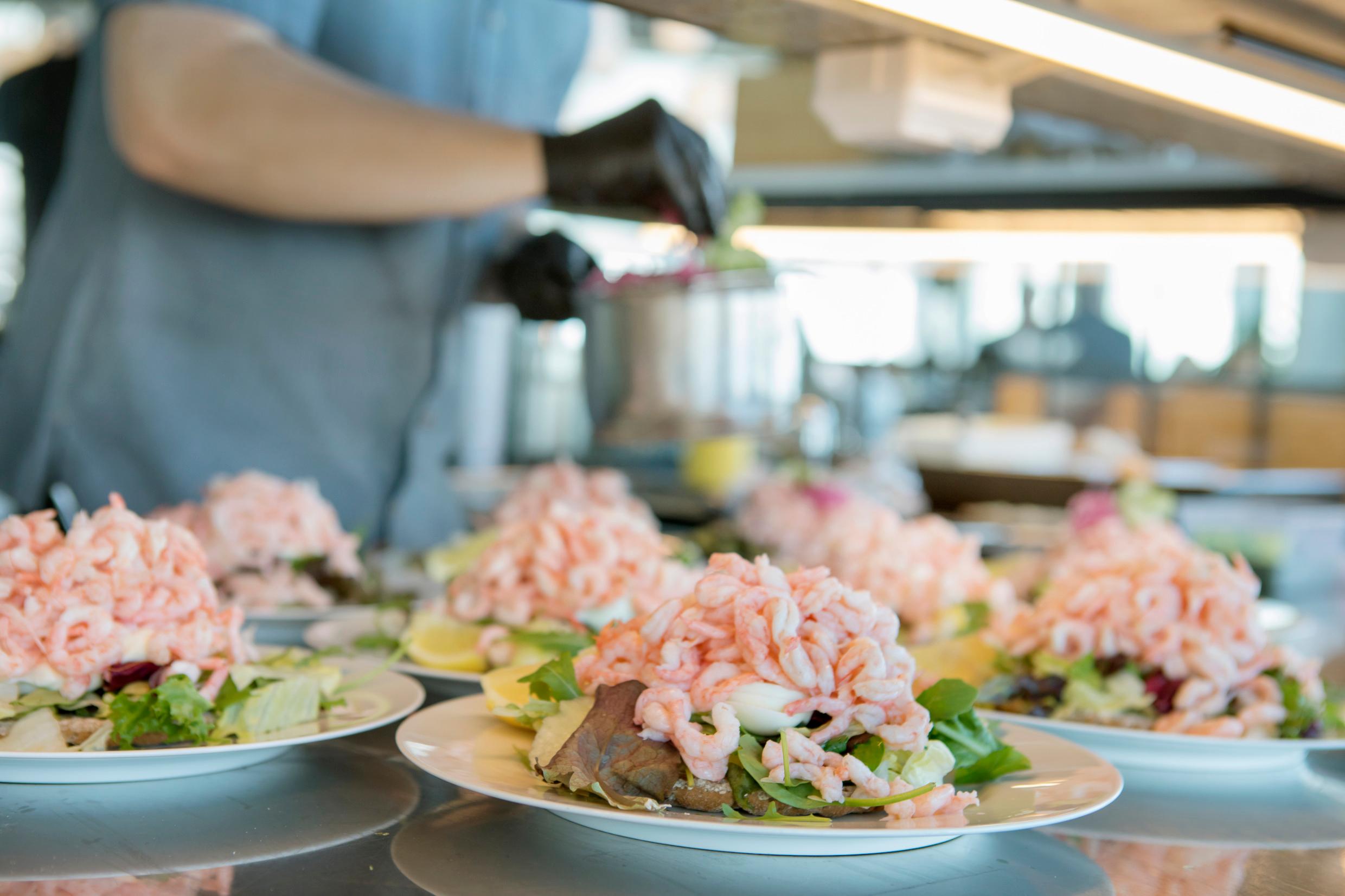 A worktop with plates with shrimp sandwiches on. One example of typically Swedish food.