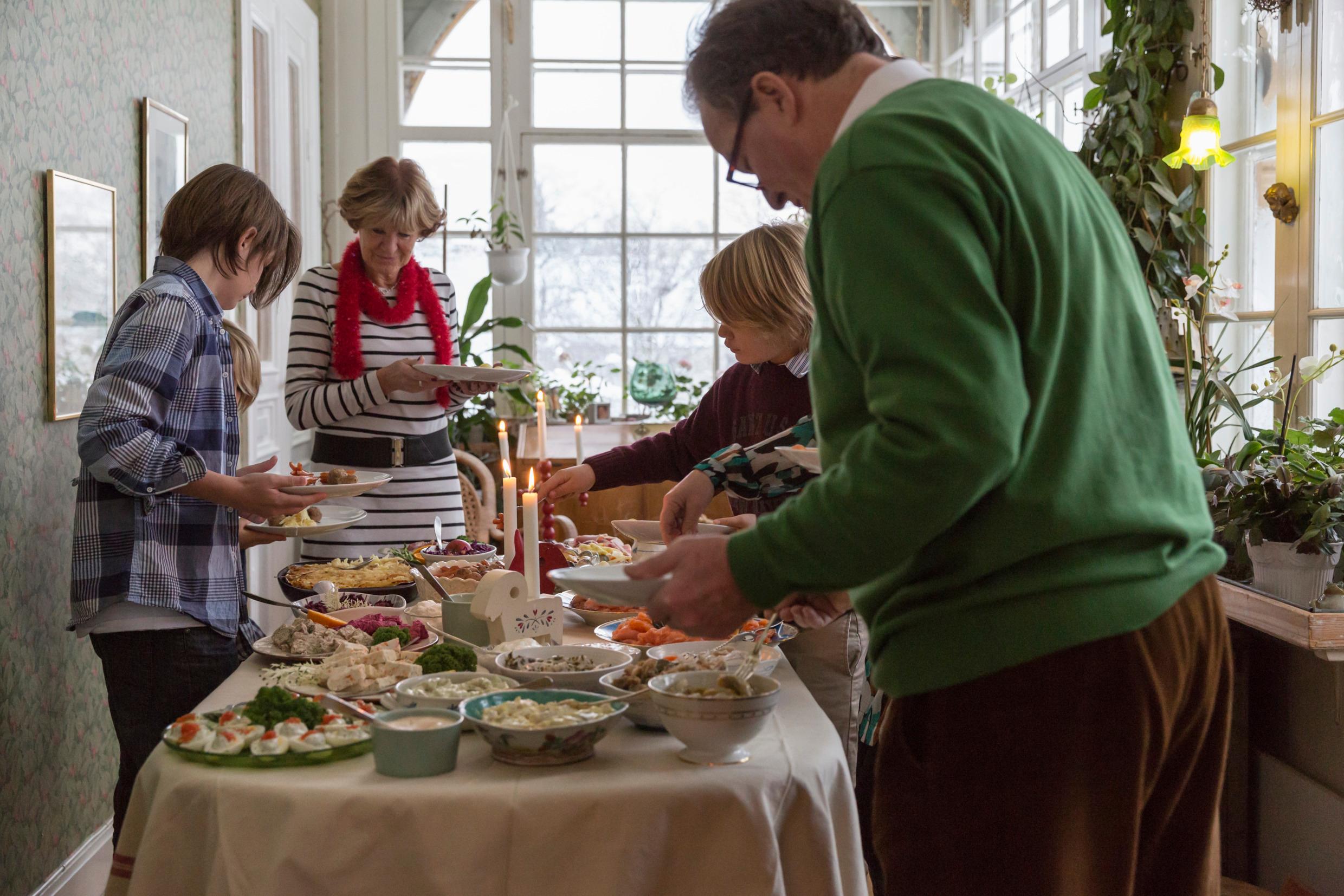 A man, a woman and three children are taking food from a buffet table.