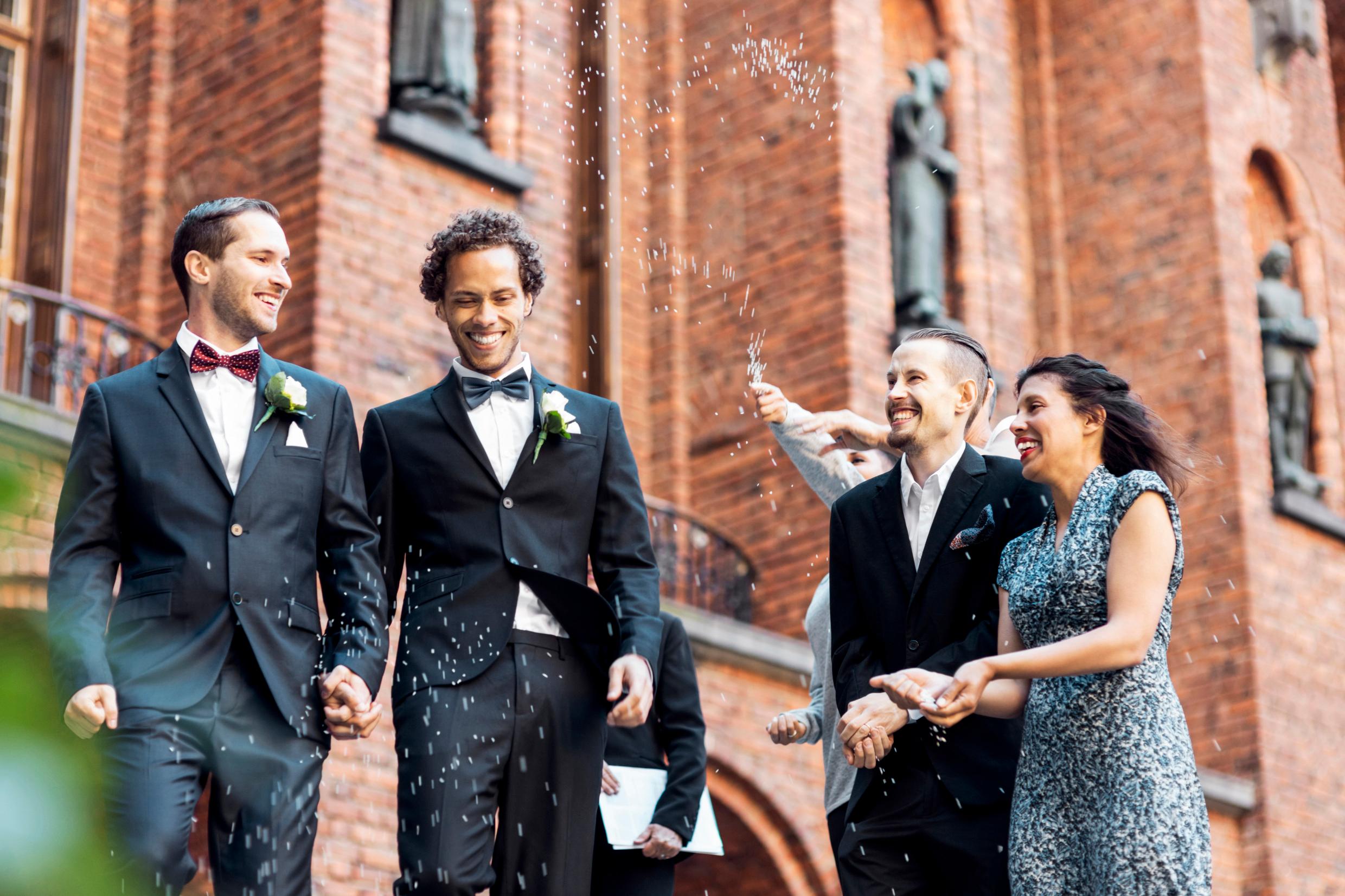 Four well-dressed people outside, smiling.