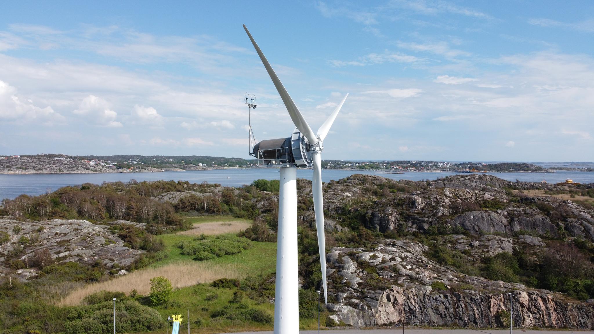 A wind turbine with an island and the sea in the background.