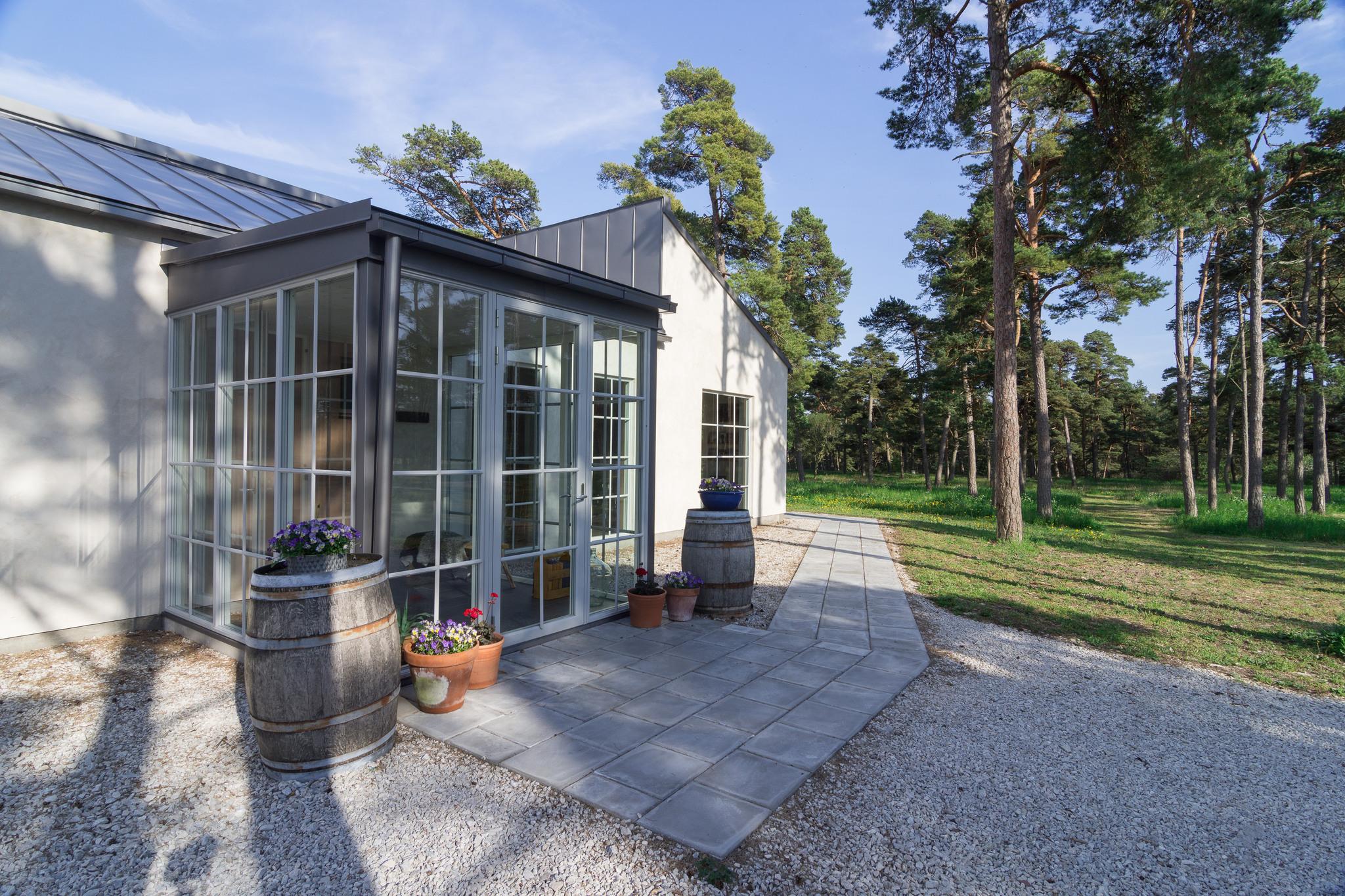 A building with a glass veranda situated among pine trees.