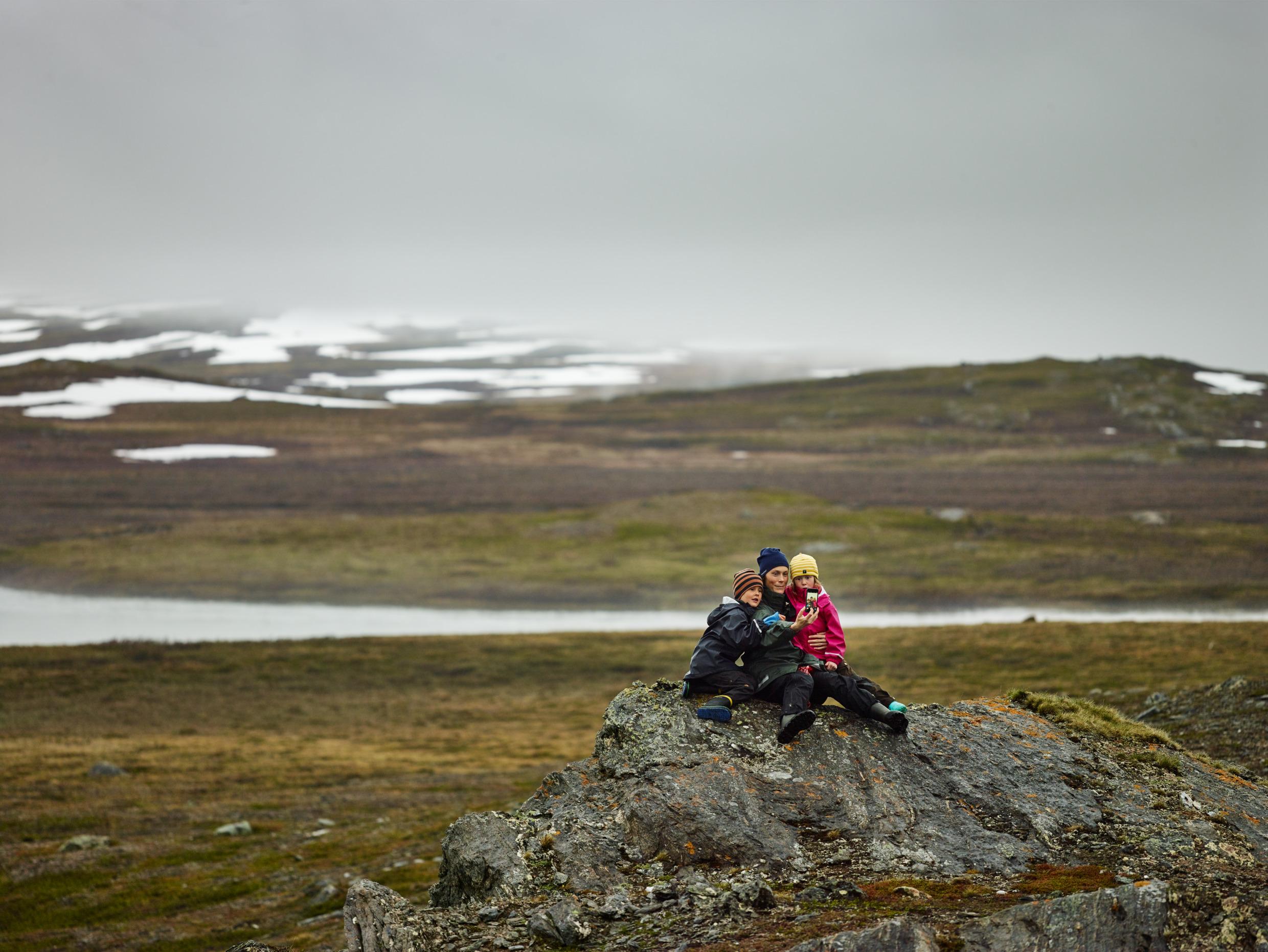 Three people sitting on a rock, enjoying Swedish wildlife in the north.