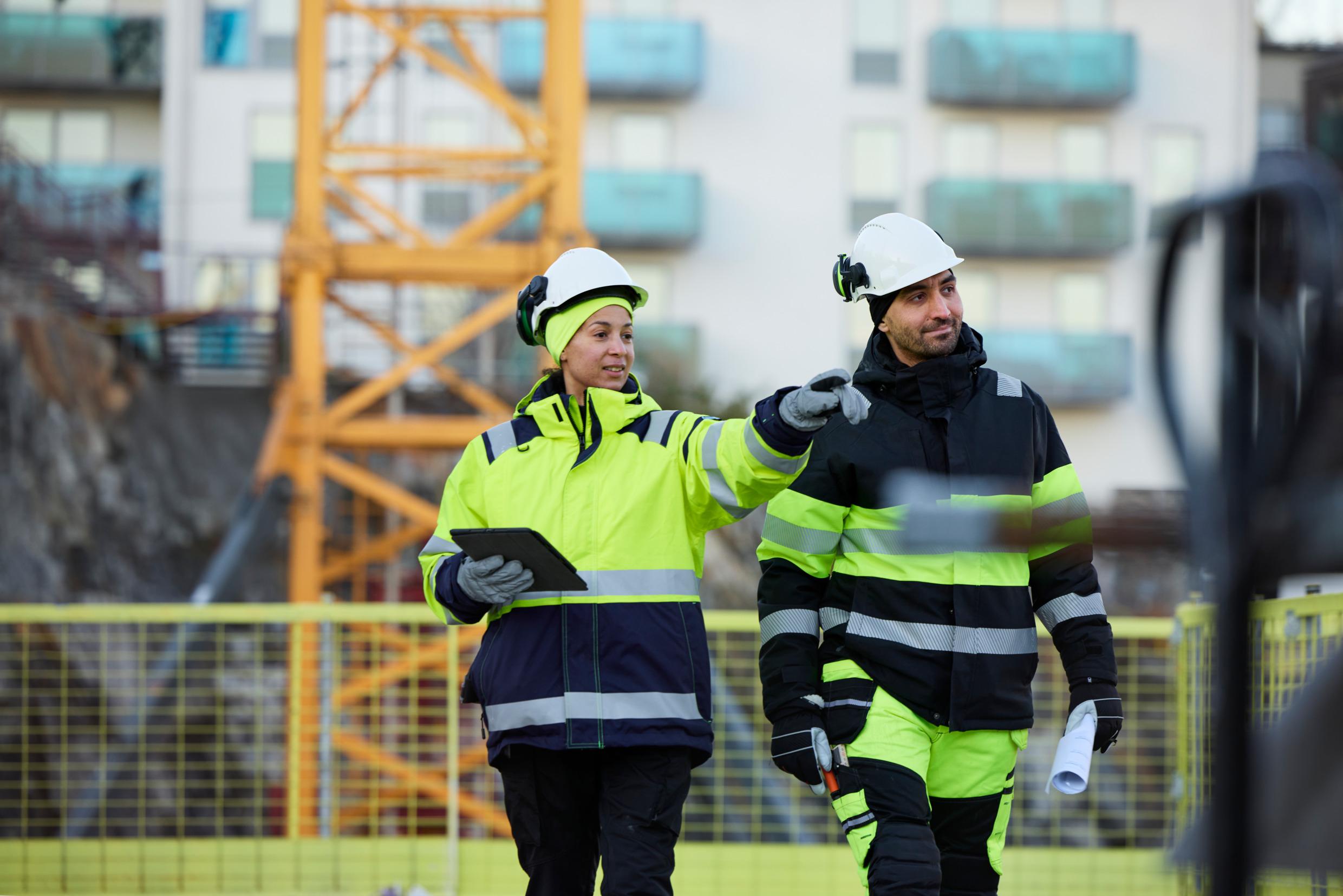 A man and a woman in hardhats at a construction site.