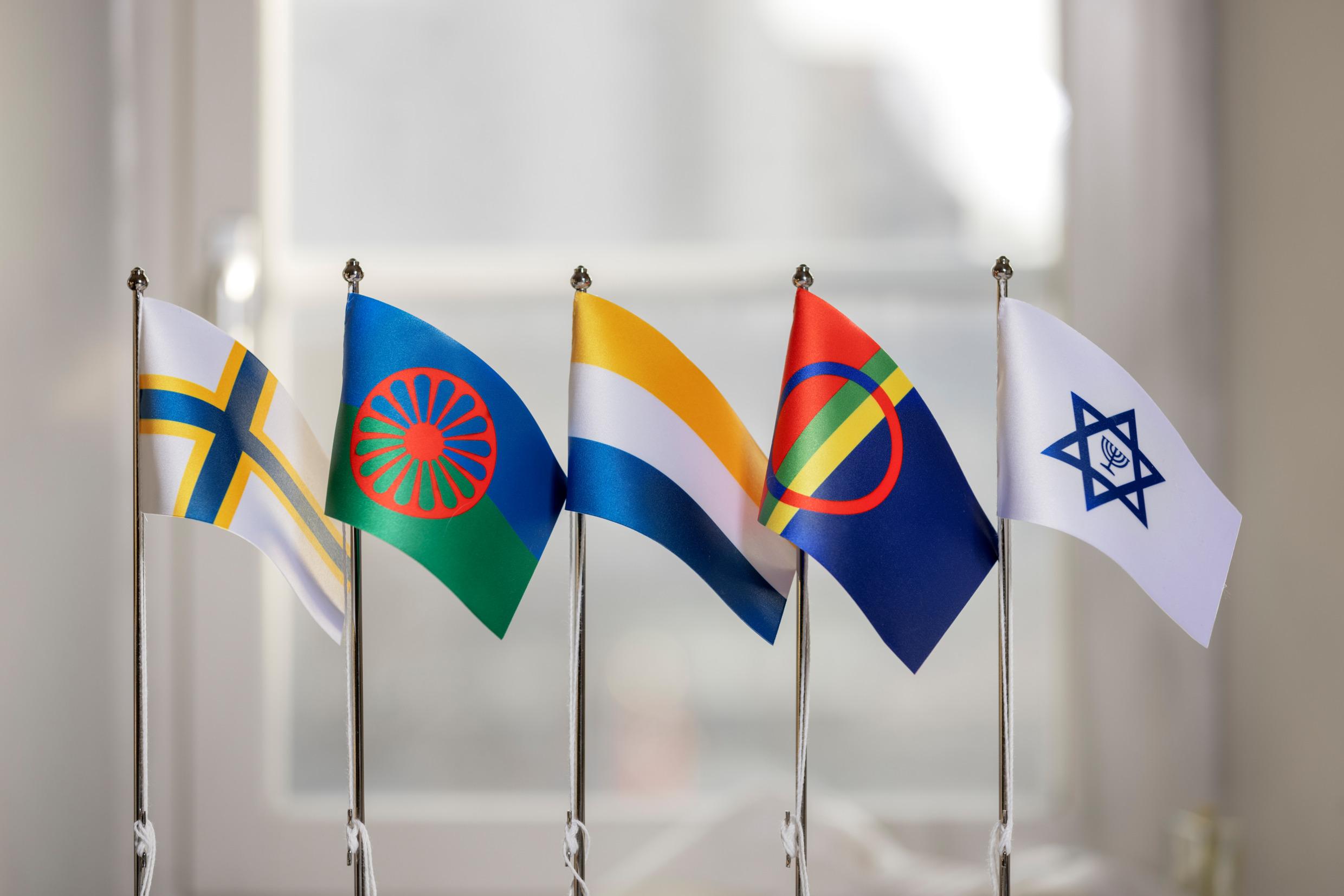 Five flags in front of a window.