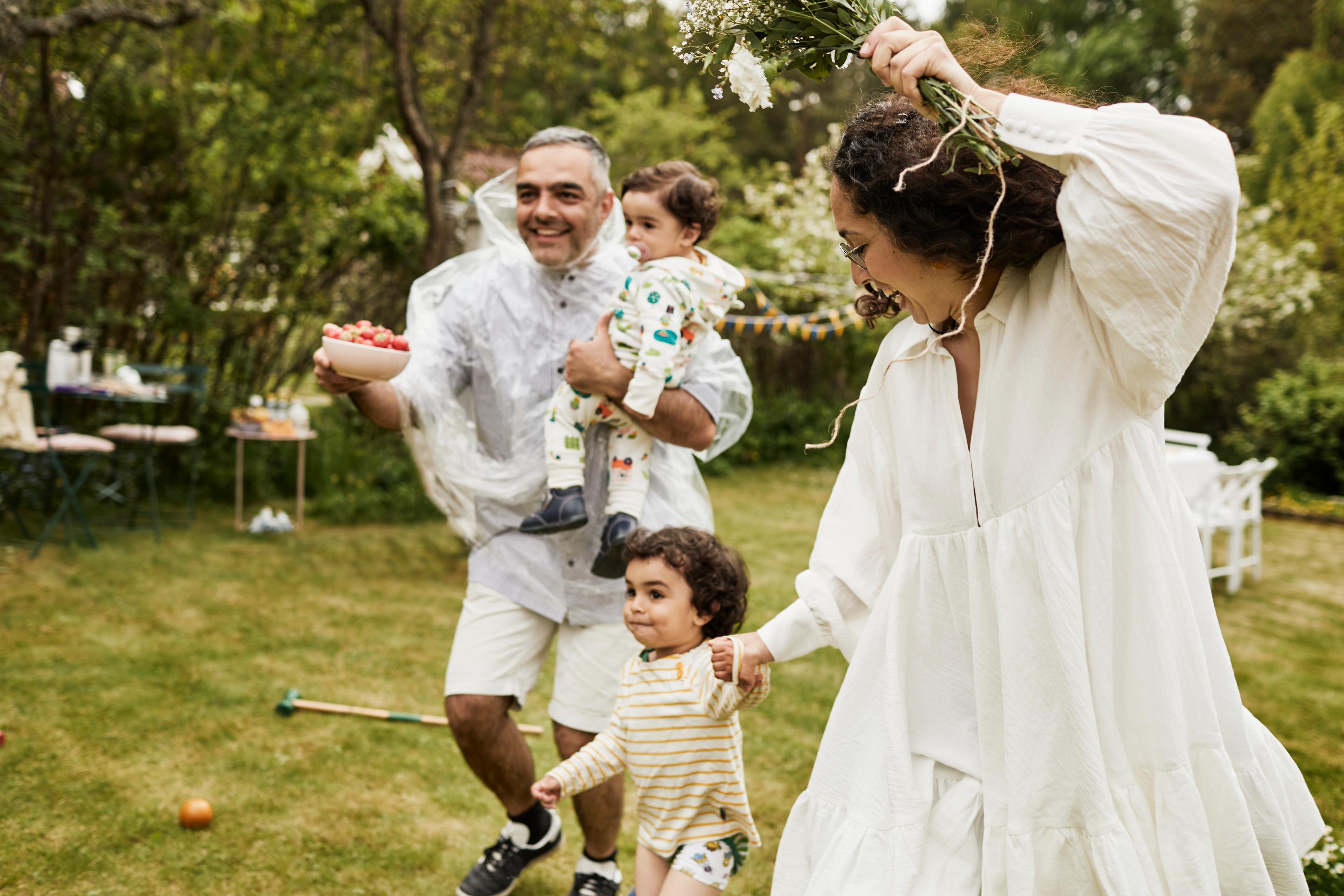 A man, woman and children run across a lawn gleefully.