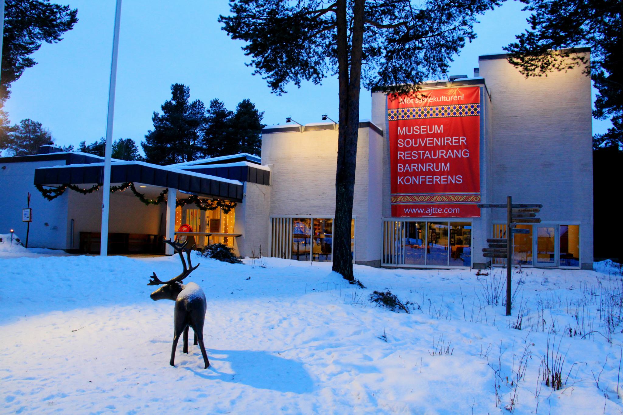A museum building in the snow. In front is a reindeer sculpture.