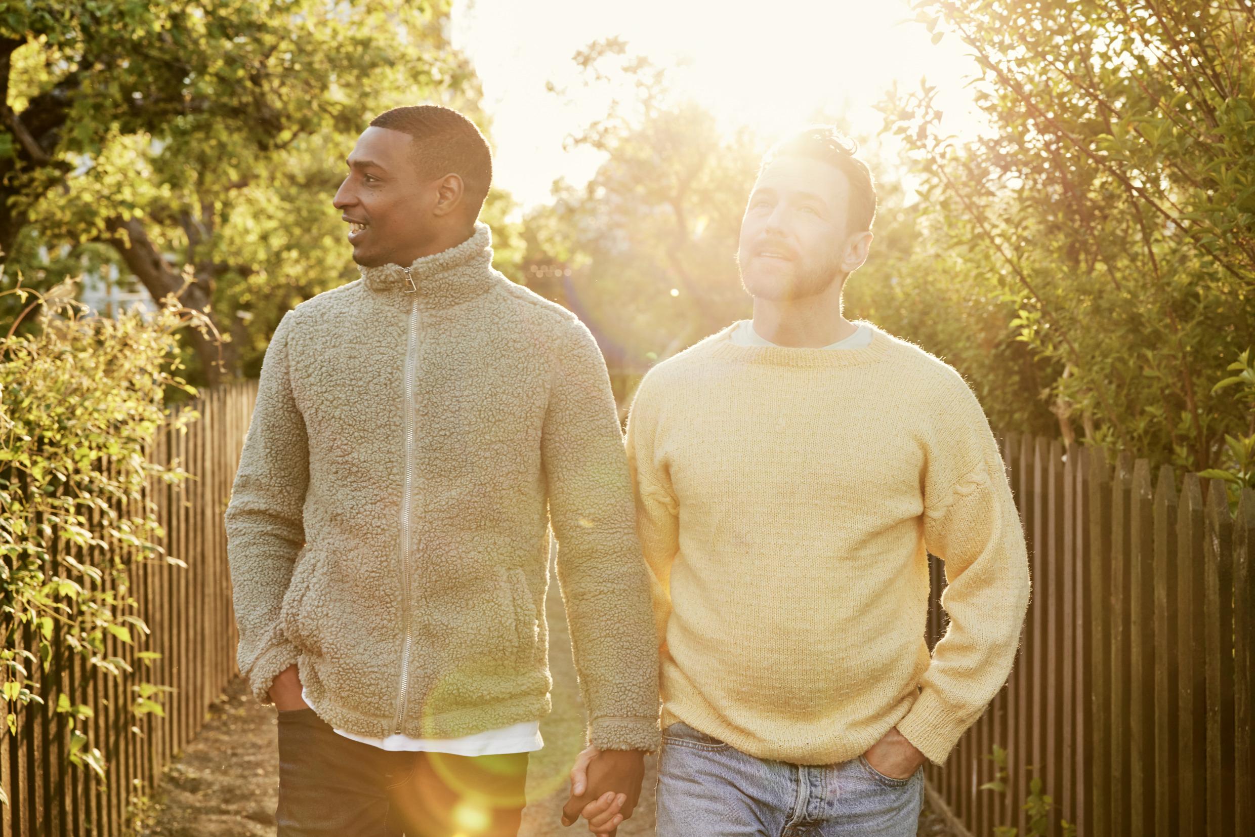 Two men walking in nature and holding hands.