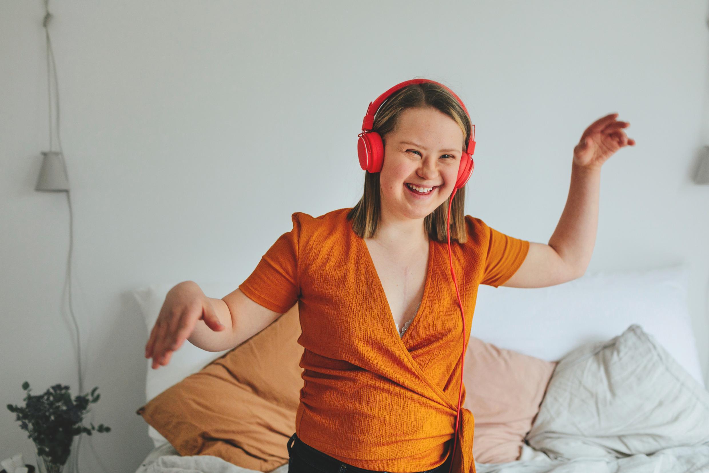 A girl with headphones on in the middle of a dance step.