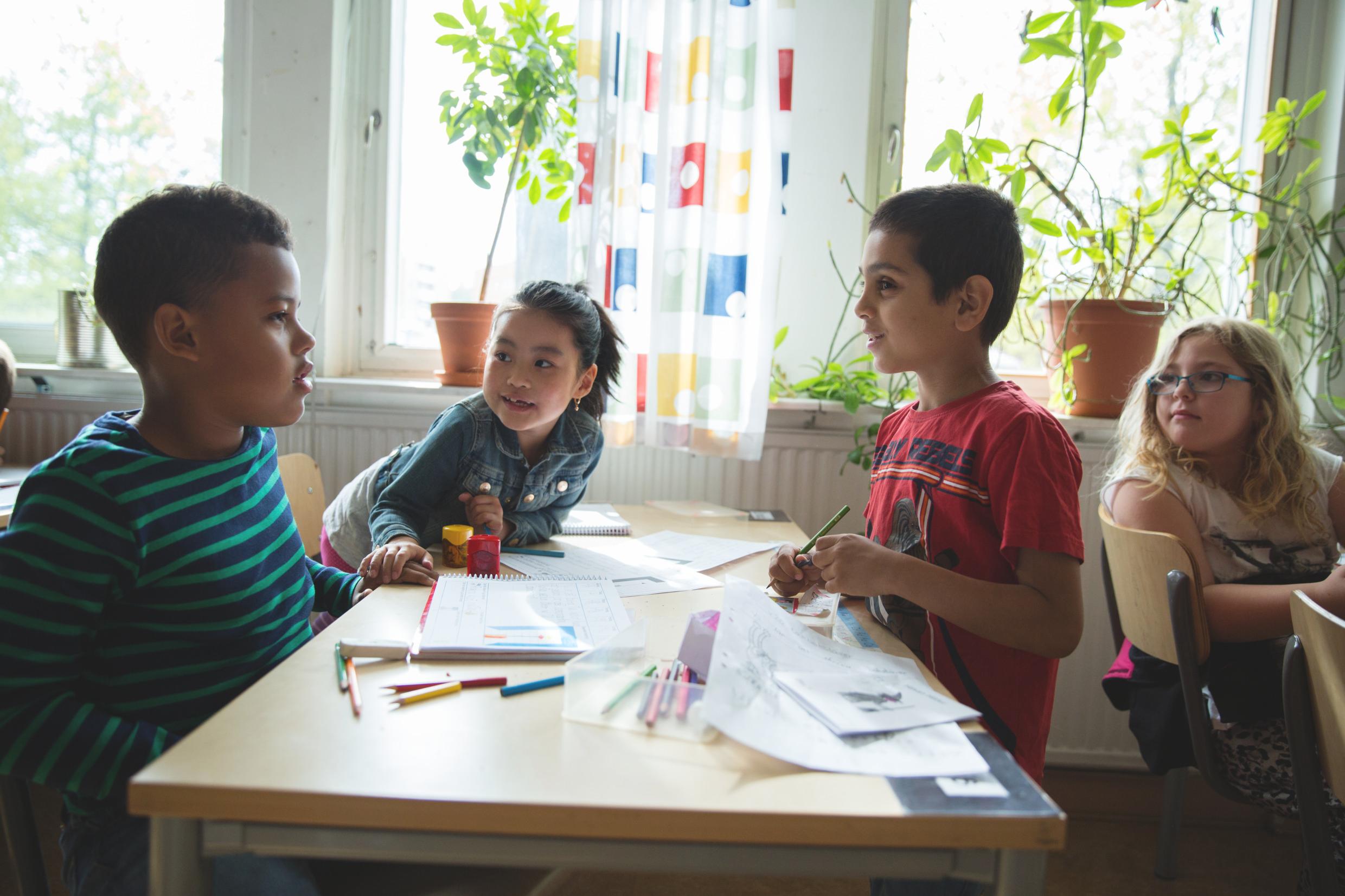 Children sitting together at a table in a classroom.