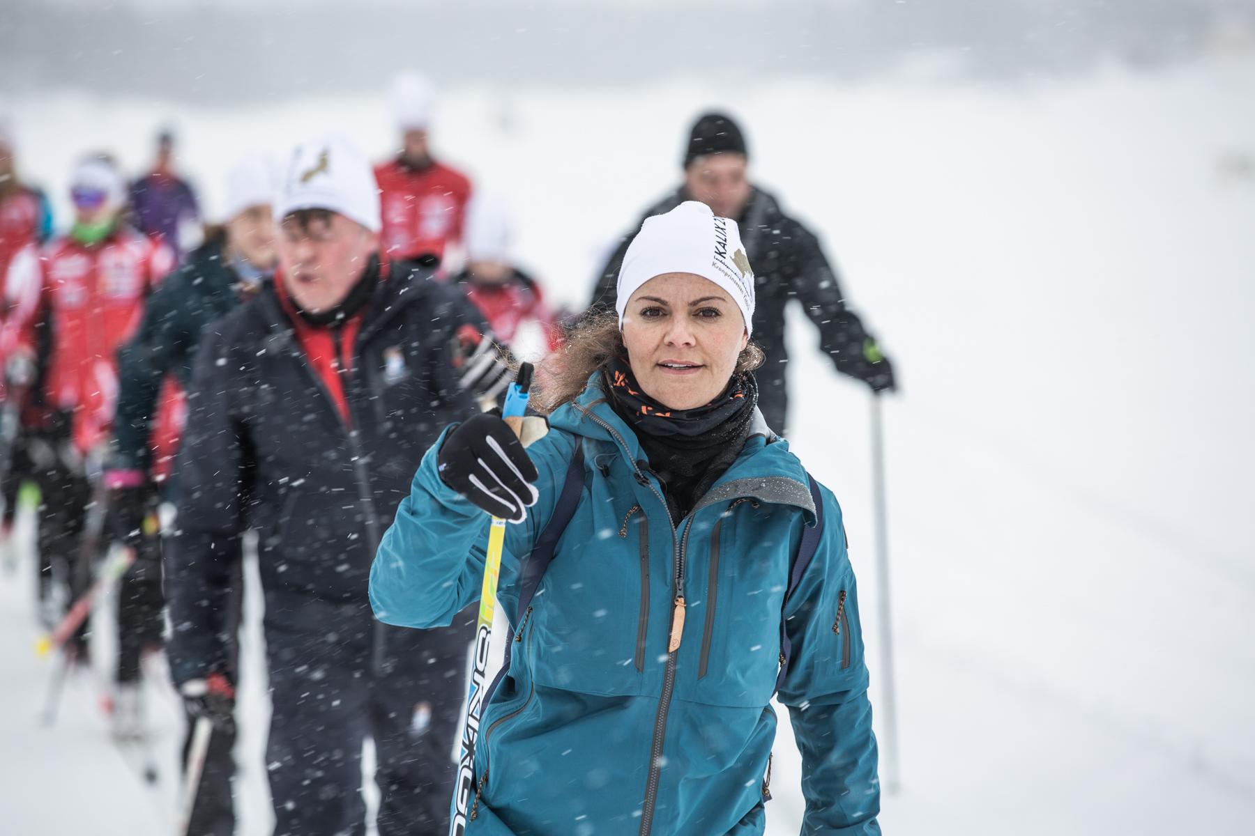 Crown Princess Victoria in sporty winter clothes, skiing together with other people.