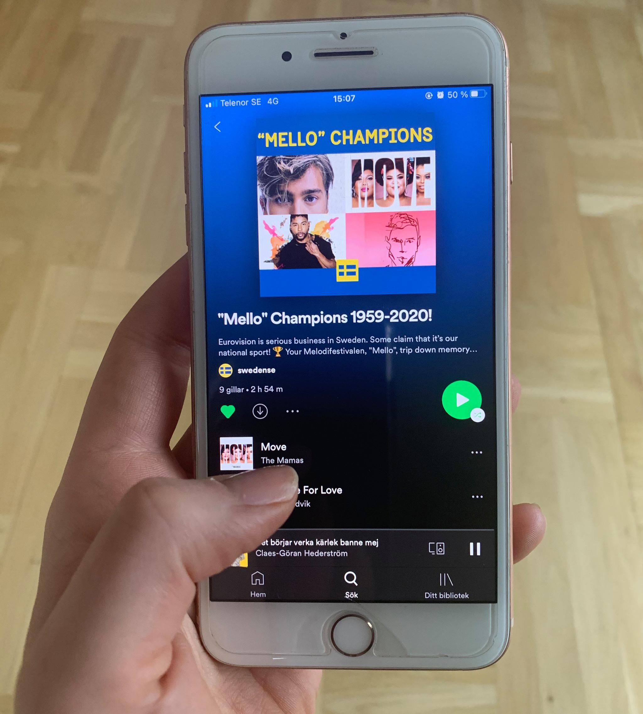 A hand holding a mobile phone with Spotify on the screen.