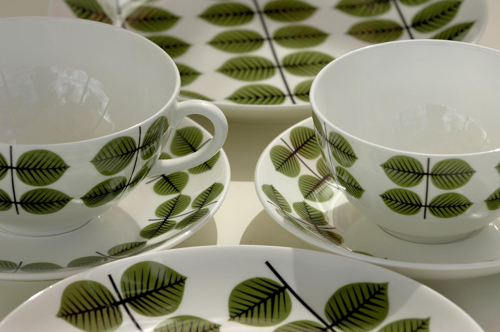 Porcelaine cups and saucers with a green leaf pattern.
