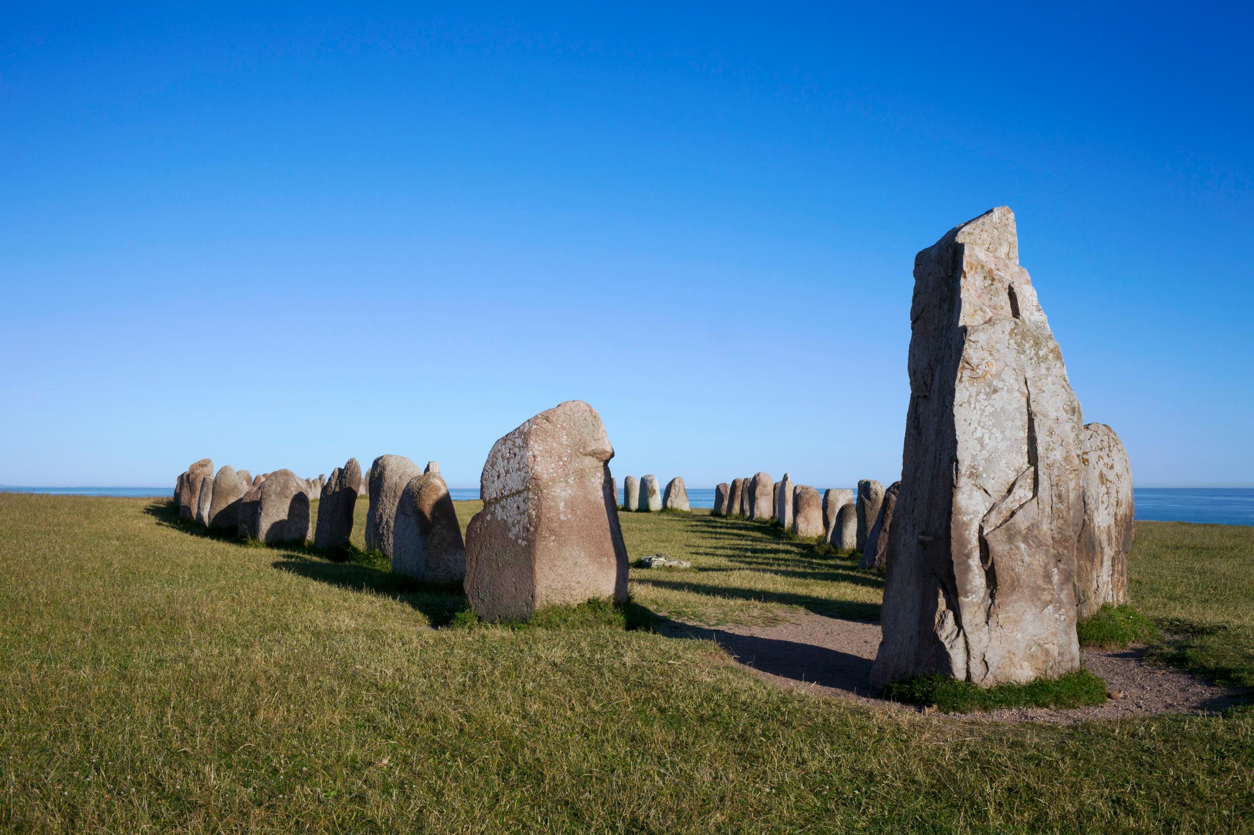 Ale's Stones stand on a field with the ocean in the background.