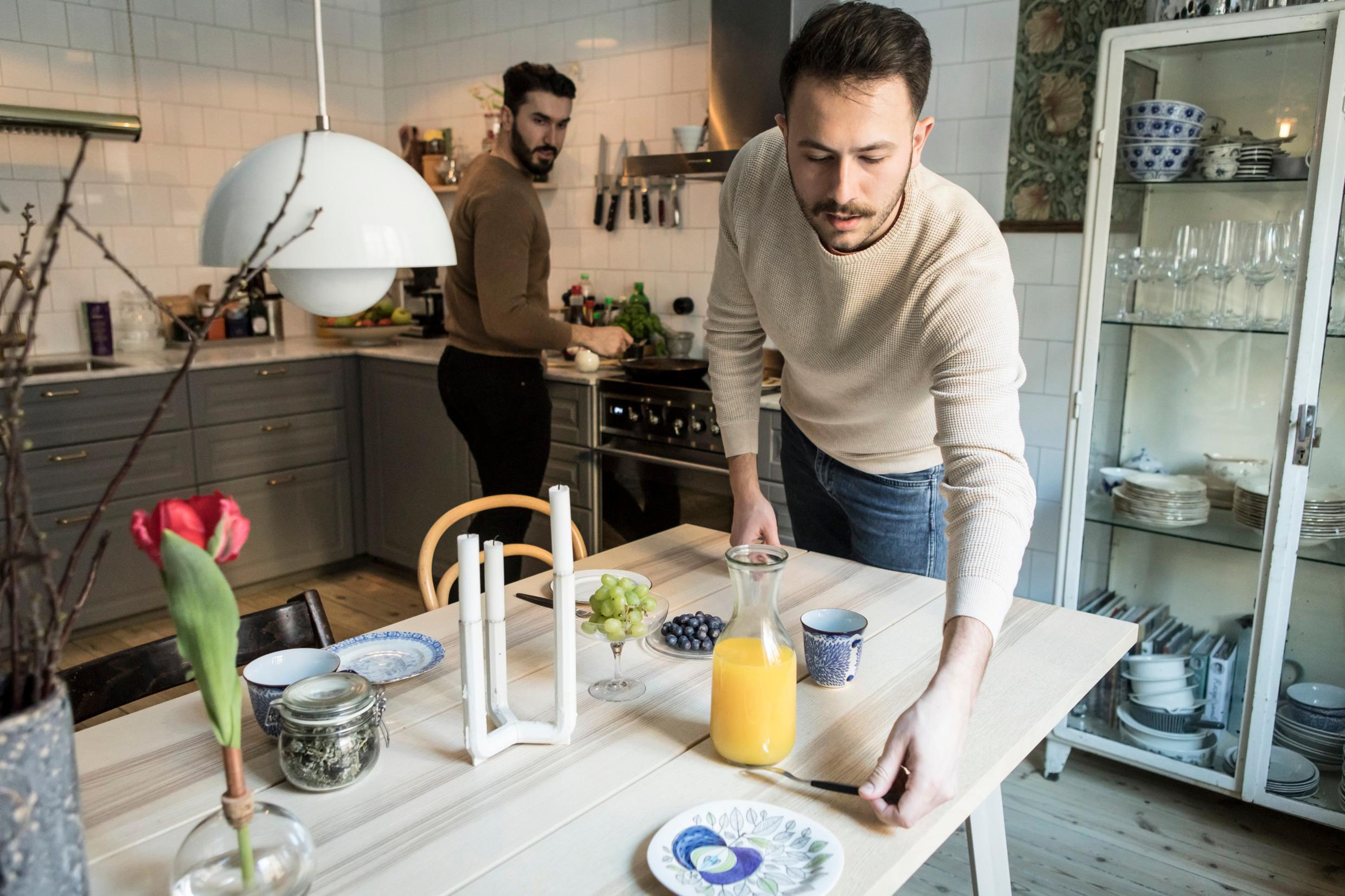 Two men in a kitchen are preparing breakfast.