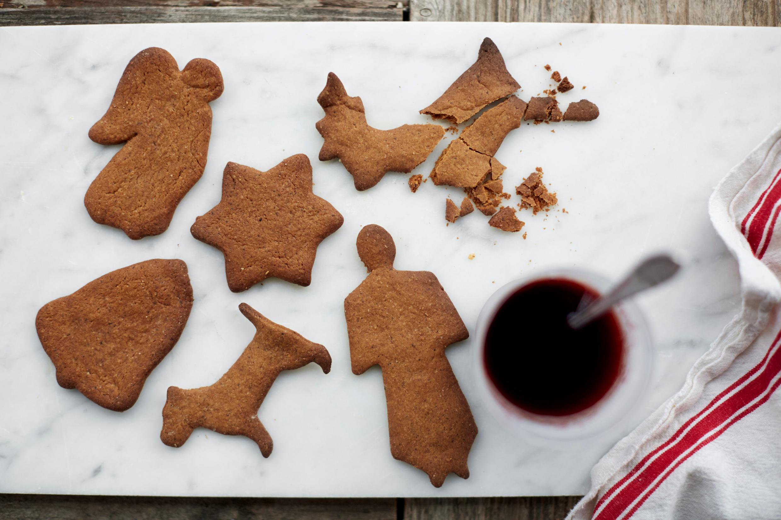 A table with gingerbread cookies in different shapes and a cup of mulled wine.