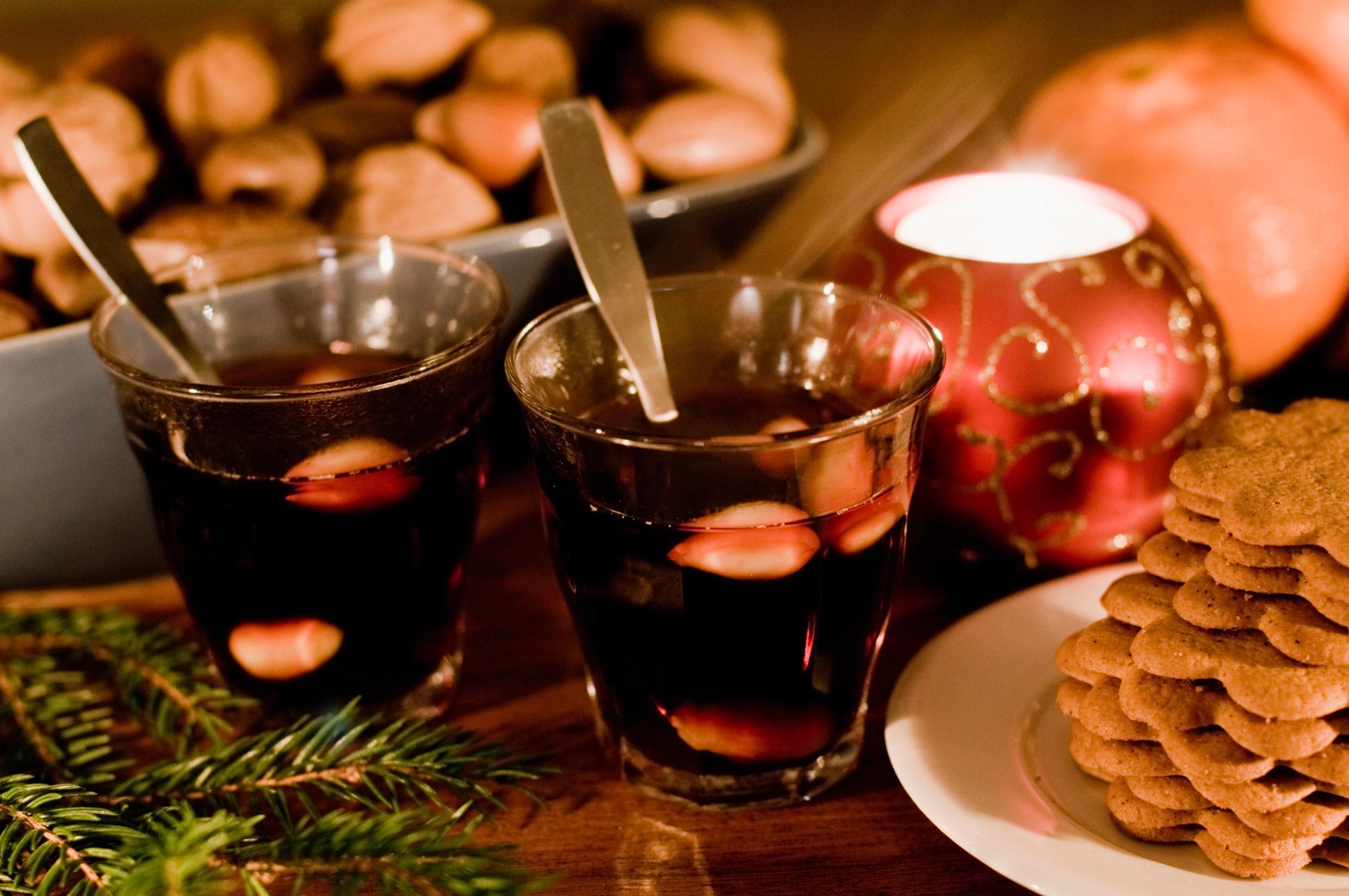 A table laid with two glasses of glögg and gingerbread biscuits.