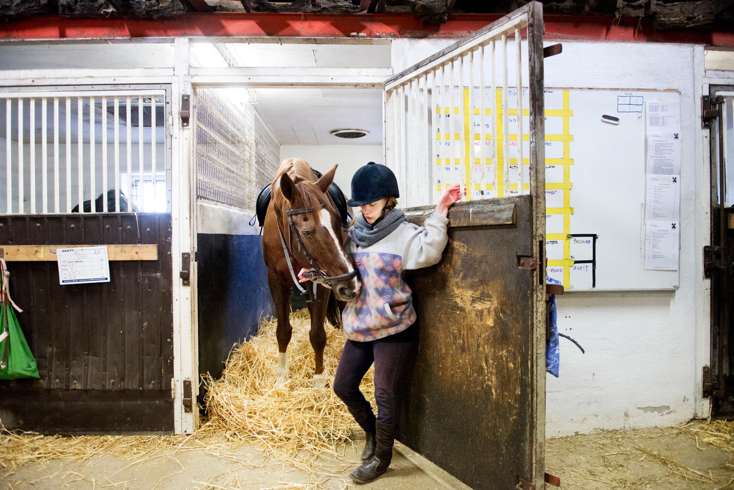 A girl and a horse in a stable.