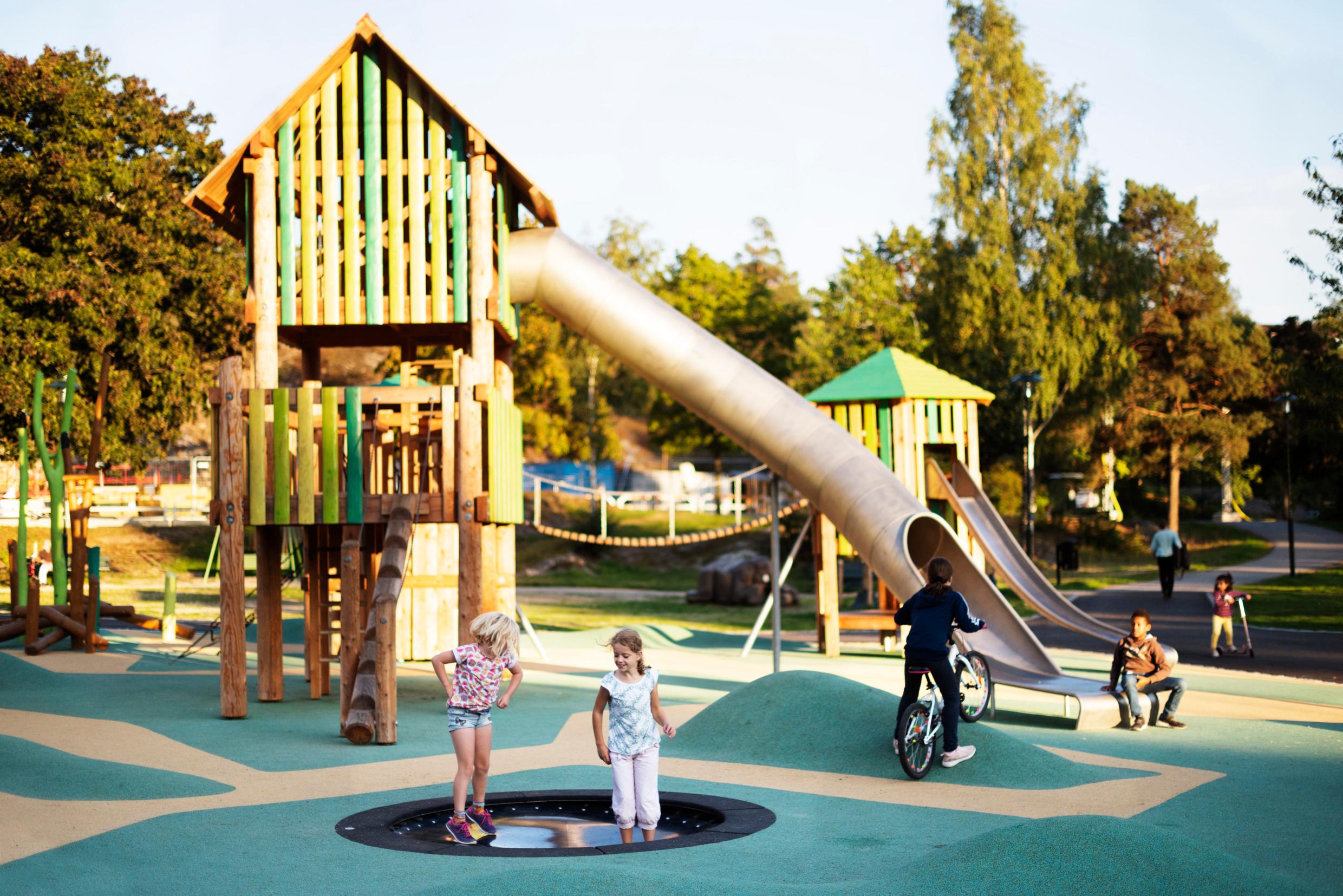 Children playing at a playground in a green area.