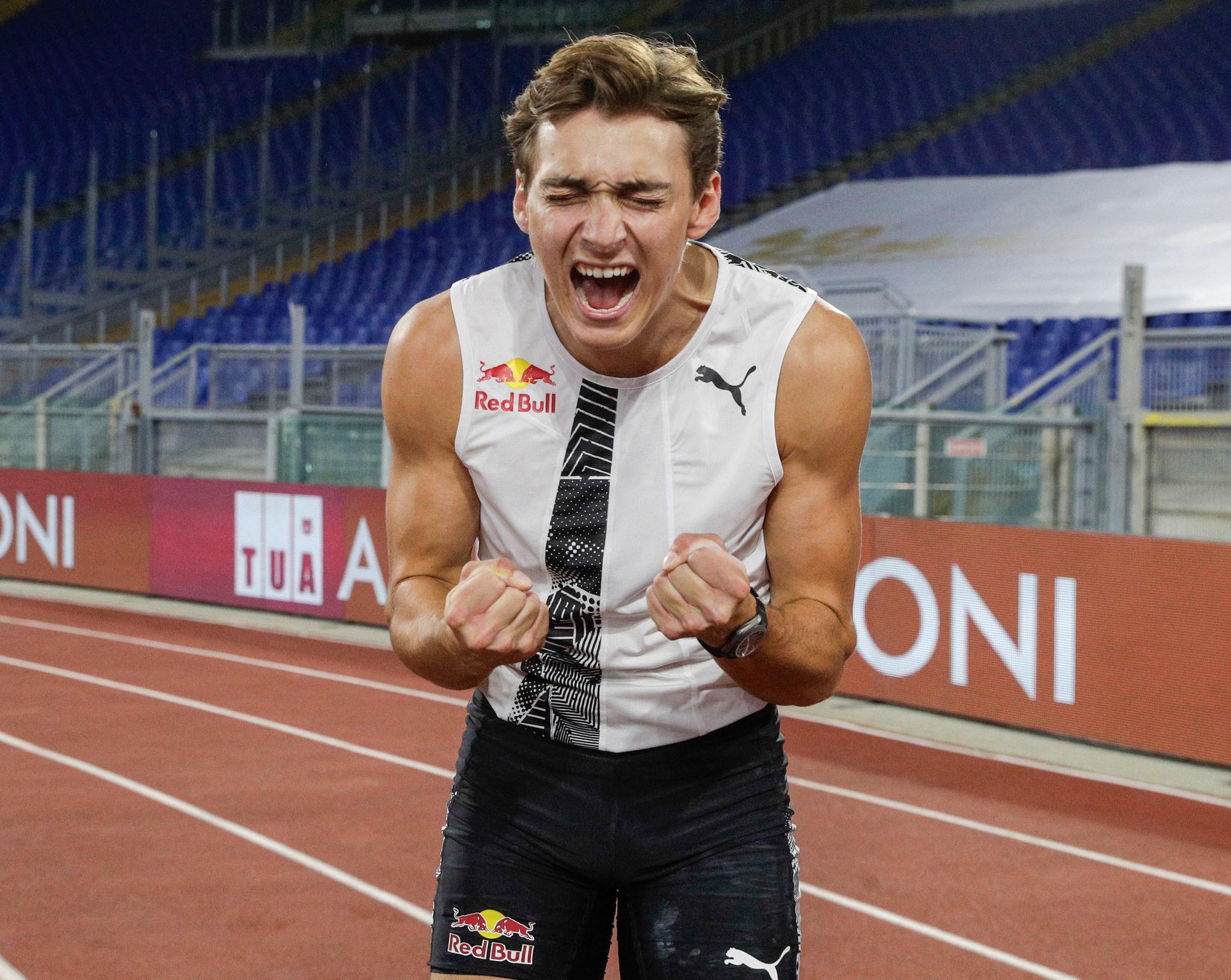 Armand Duplantis in a sports arena making a winning gesture by clenching his fists.