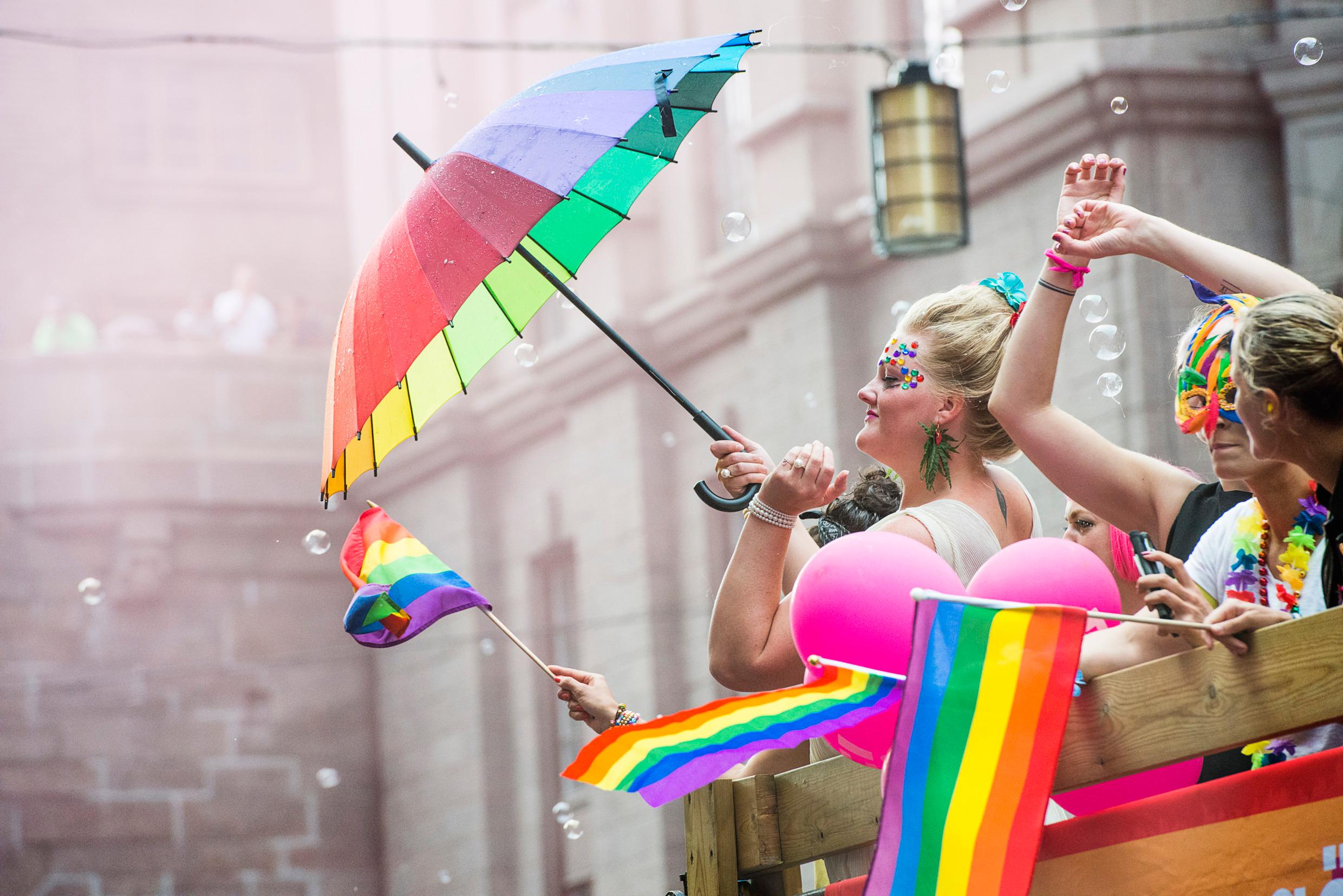 People taking part in a pride festival, with rainbow-coloured flags and accessories.