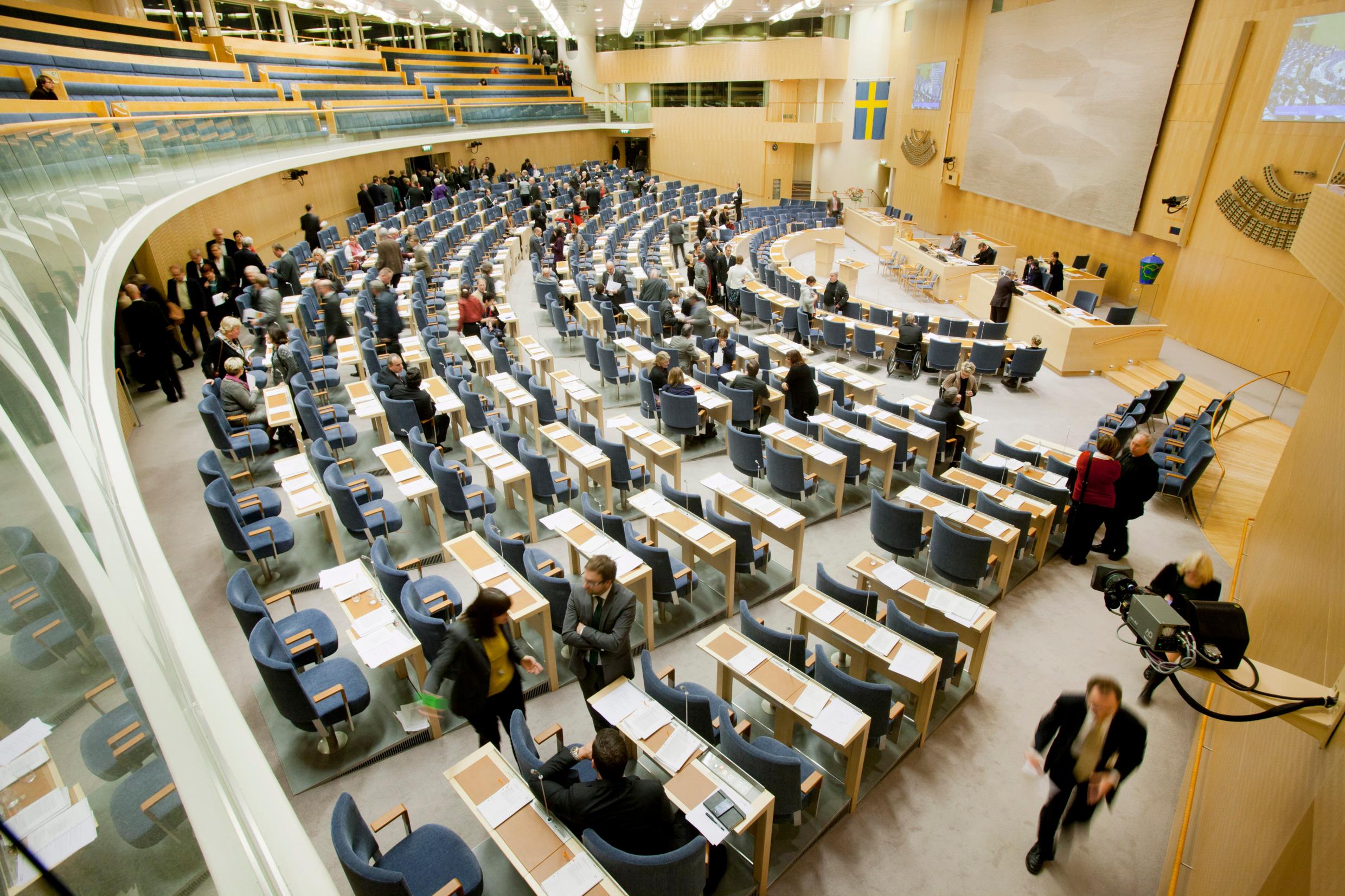 The chamber of the Swedish parliament, with desks and seats seen from the side.