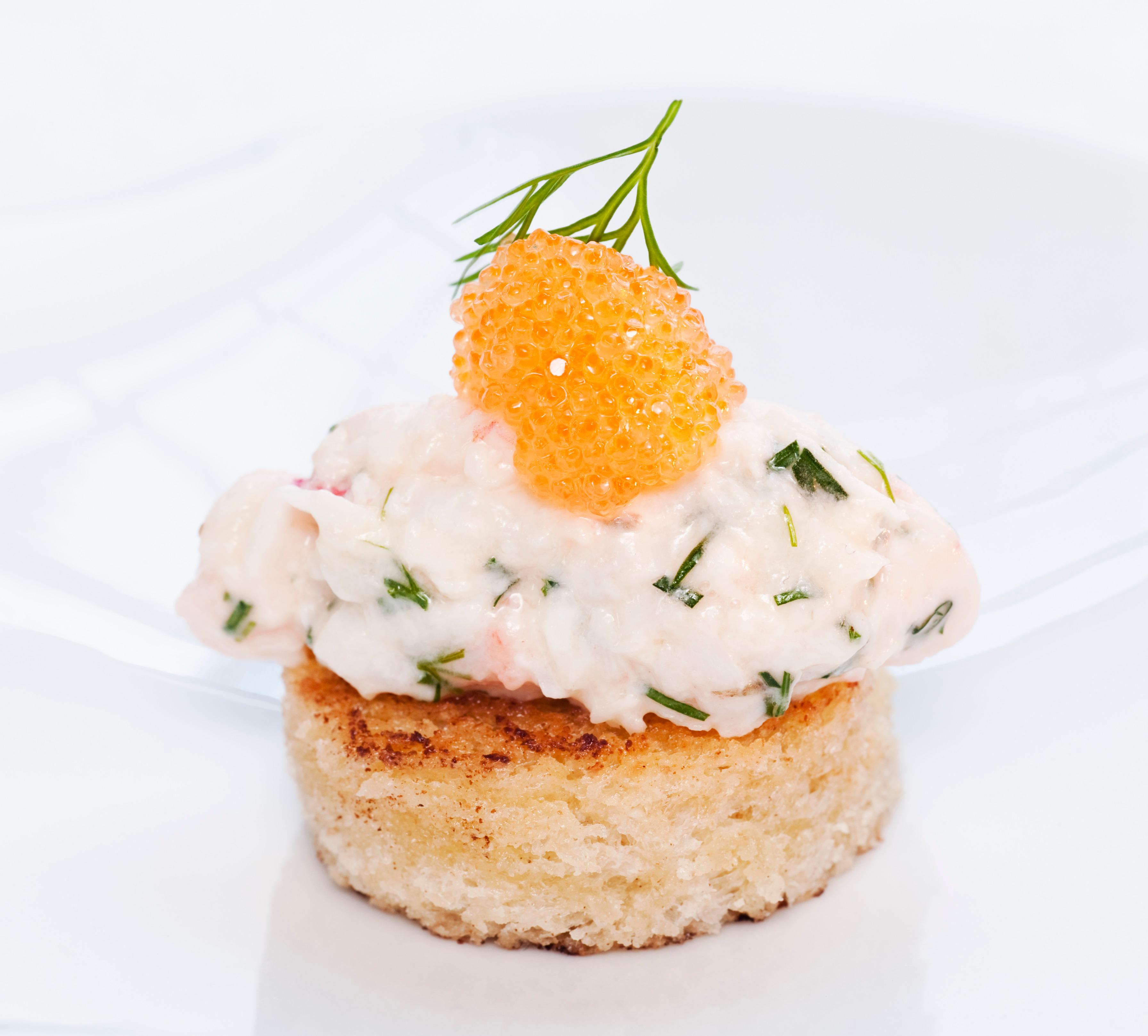 A small, round piece of bred with a mixture on top. Garnished with roe and a sprig of dill.
