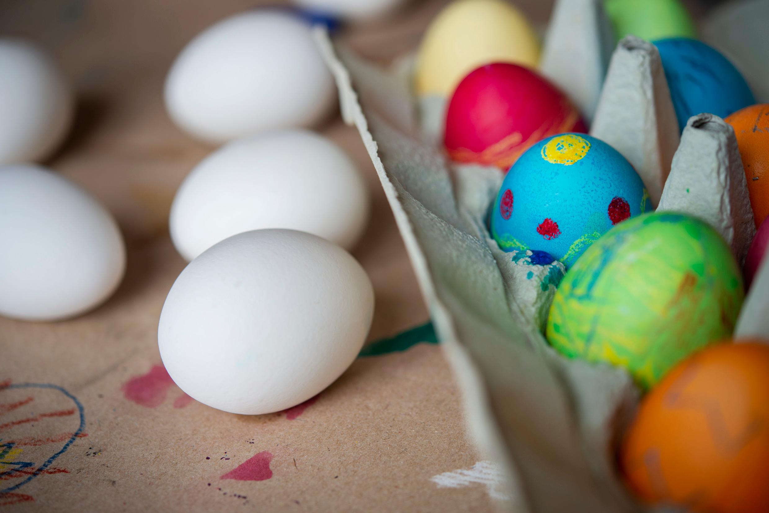 Eggs lay on a table, some painted, some unpainted.
