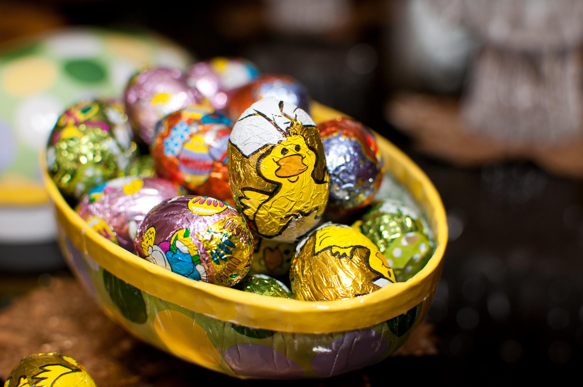 Chocolate eggs wraped in colourful foil, lying in a big cardboard egg.