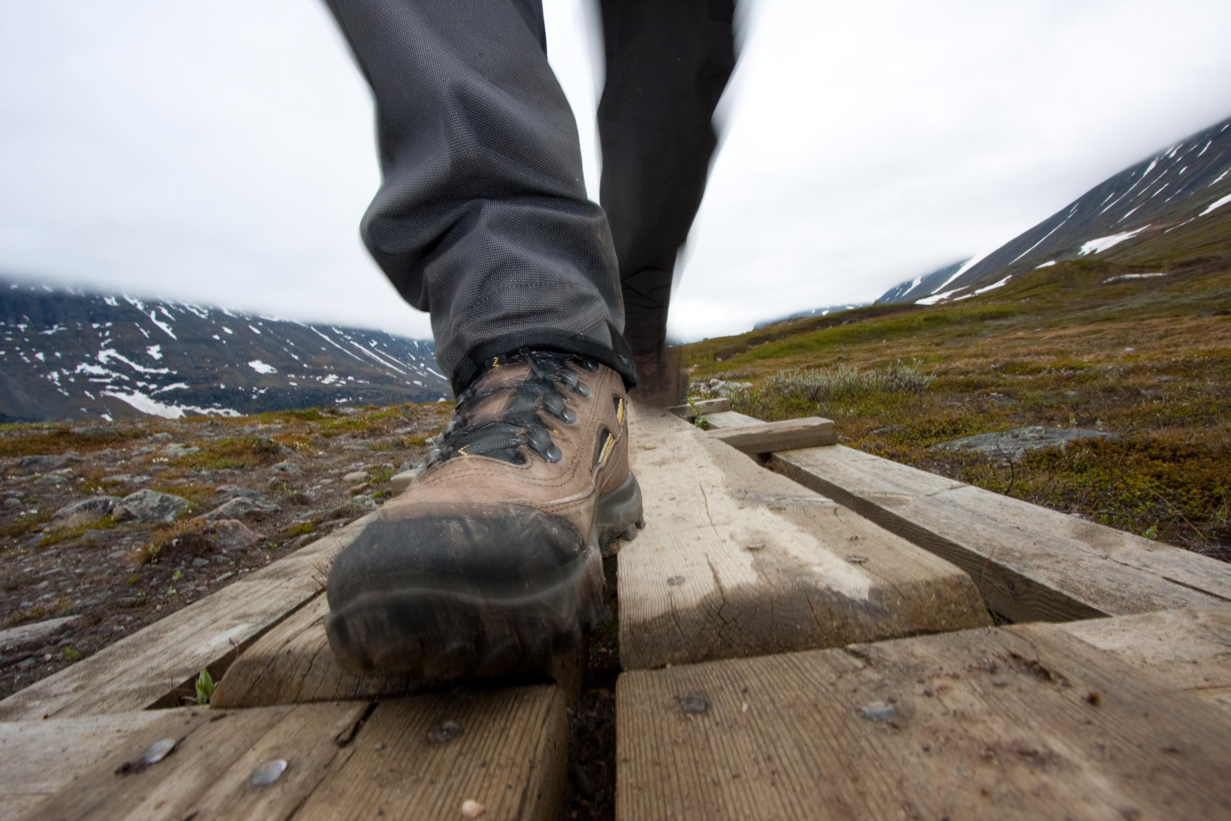 Close-up of a person's boots as he or she is walking on a foot-bridge across marsh lands around the Kebnekaise mountain region.