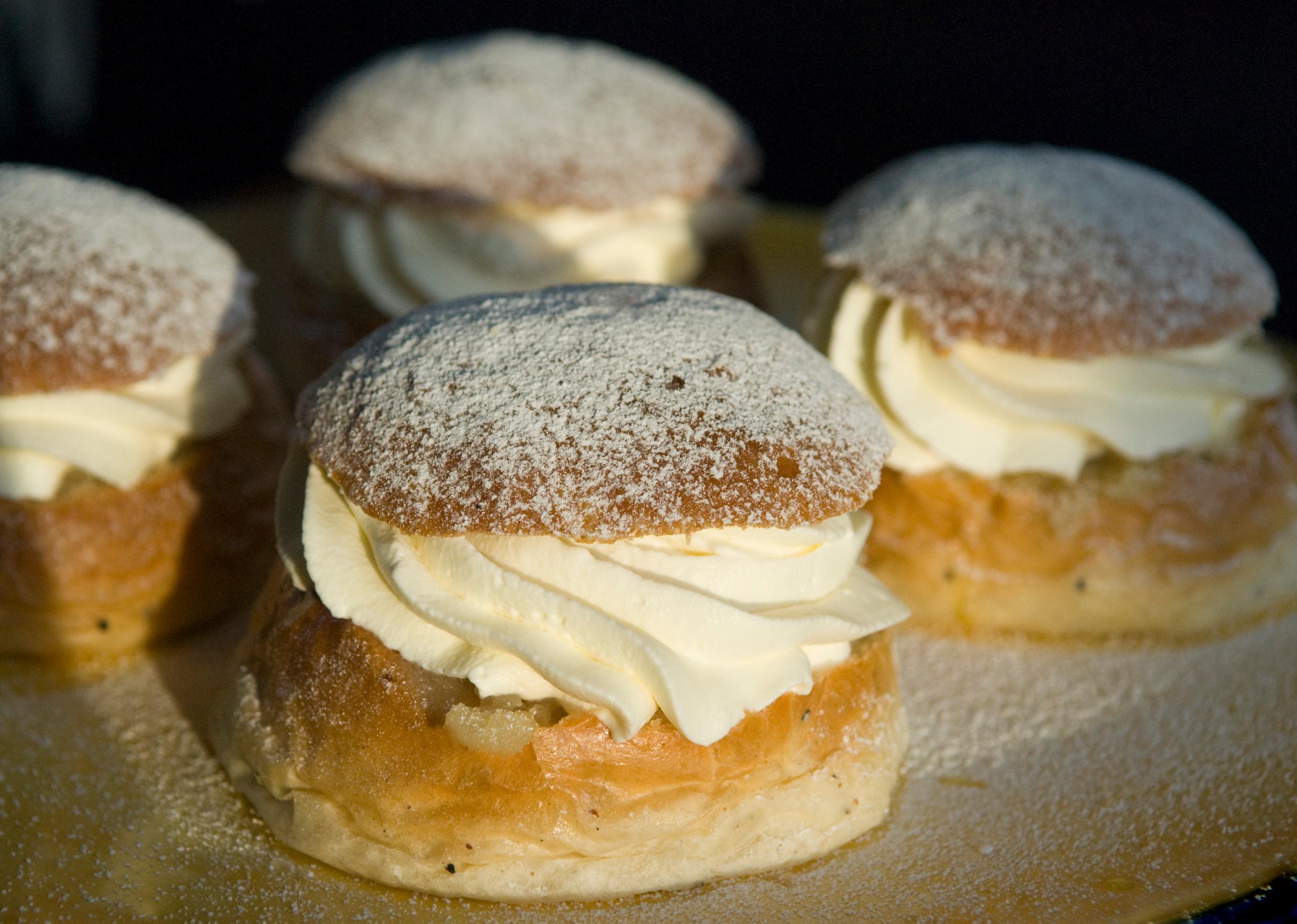 Four cream-filled wheat buns with icing sugar on top.