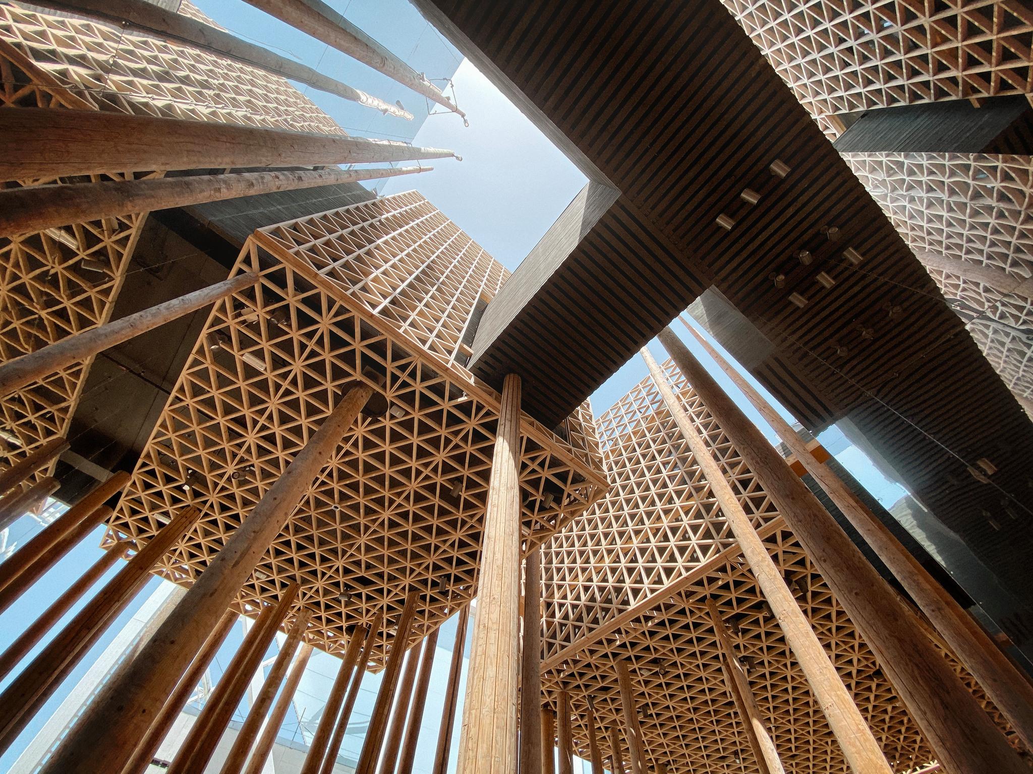 Part view of the wooden Swedish pavilion at Expo 2020, seen from below, blue sky in the background.