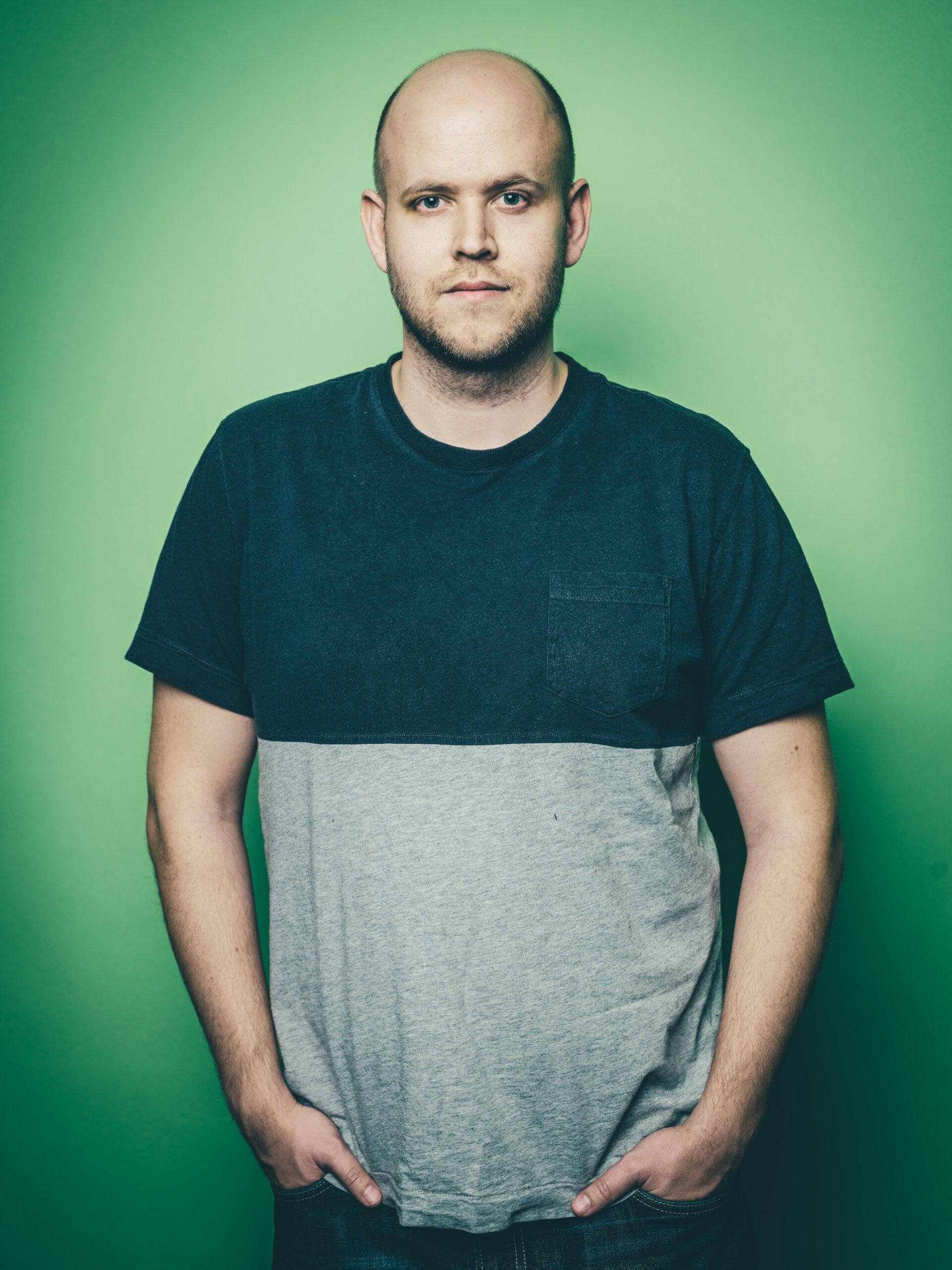 Portrait of Spotify founder Daniel Ek, standing with his hands in his pockets against a green background.