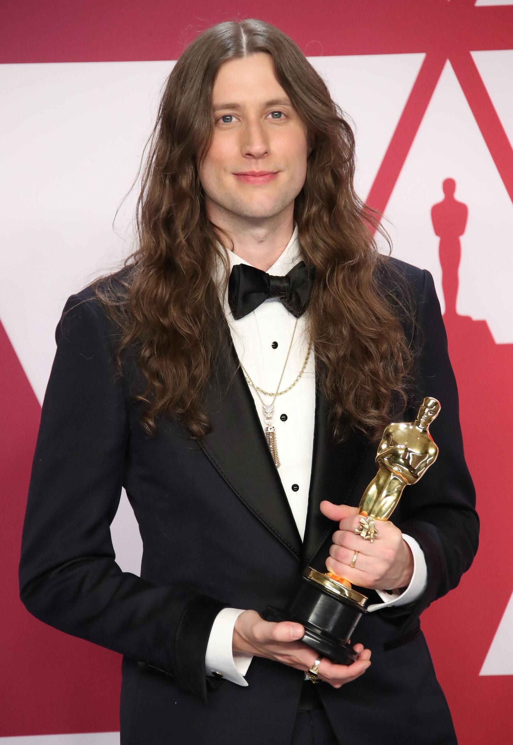 Ludwig Göransson holding an Oscar statuette in his hands.