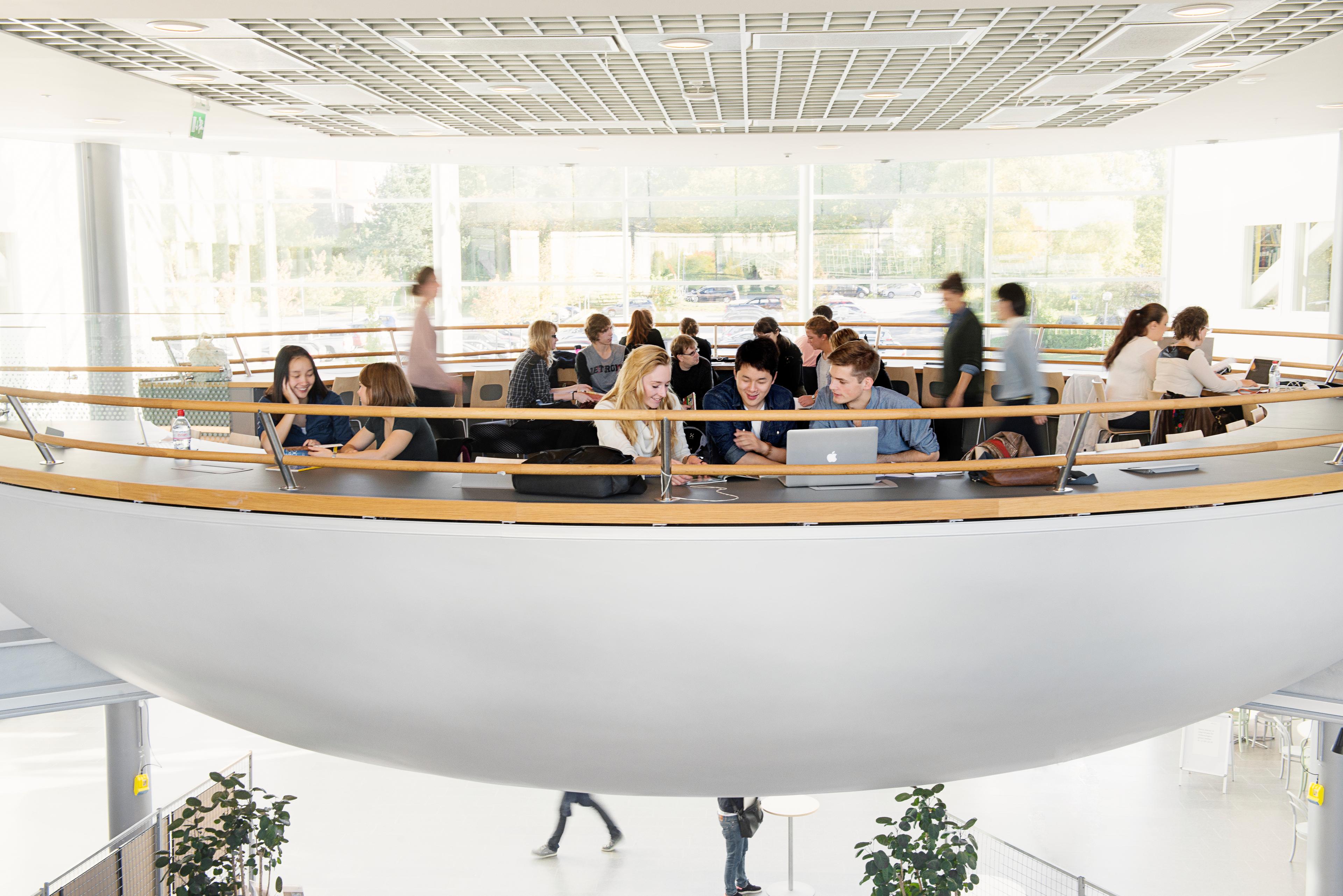 A number of students sitting in a white, bowl-shaped space that looks like it's suspended in mid-air.