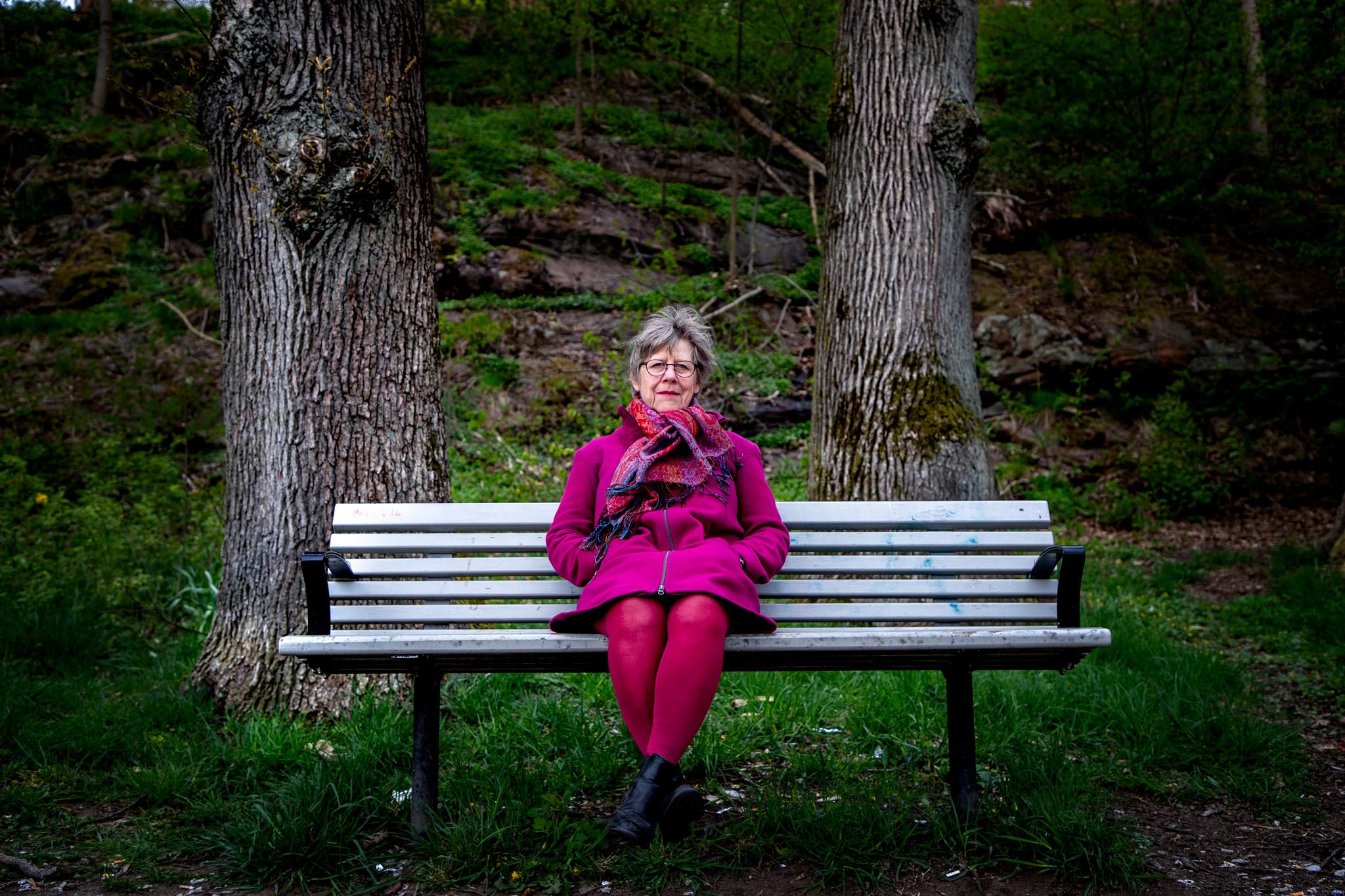 Portrait of woman with colorful clothes sitting on a bench in a park. Agnes Wold has been selected to this list of Swedish women.