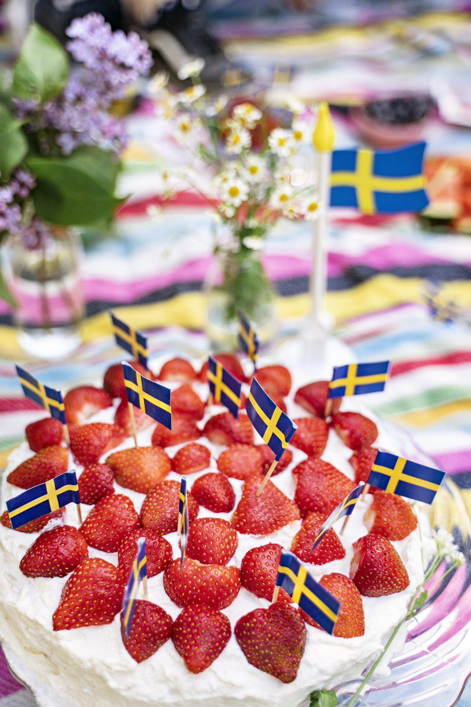 A strawberry cake decorated with many small Swedish flags.