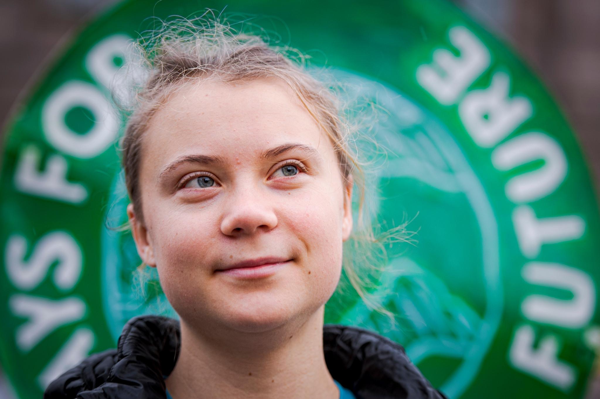 Greta Thunberg in front of a Fridays for Future sign. 
