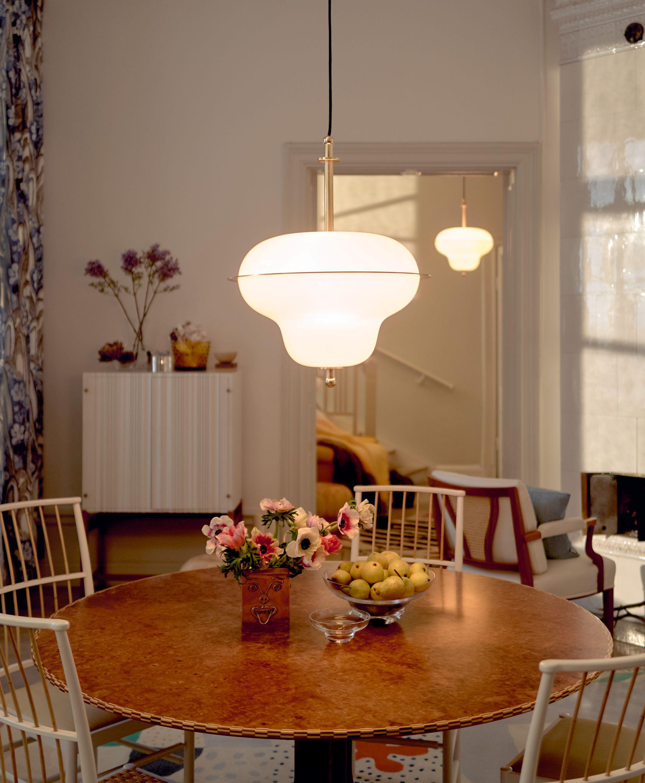 A room with a round table and chairs and a lamp hanging over the table.