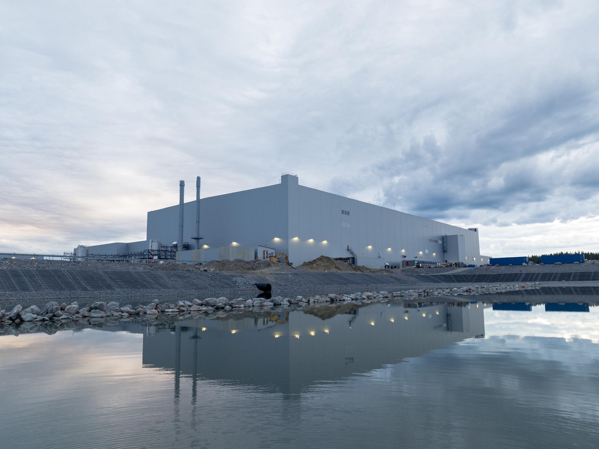 A factory building by the water, cloudy skies above. Northvolt is one of the Swedish companies that want to contribute to the electrification of transport.